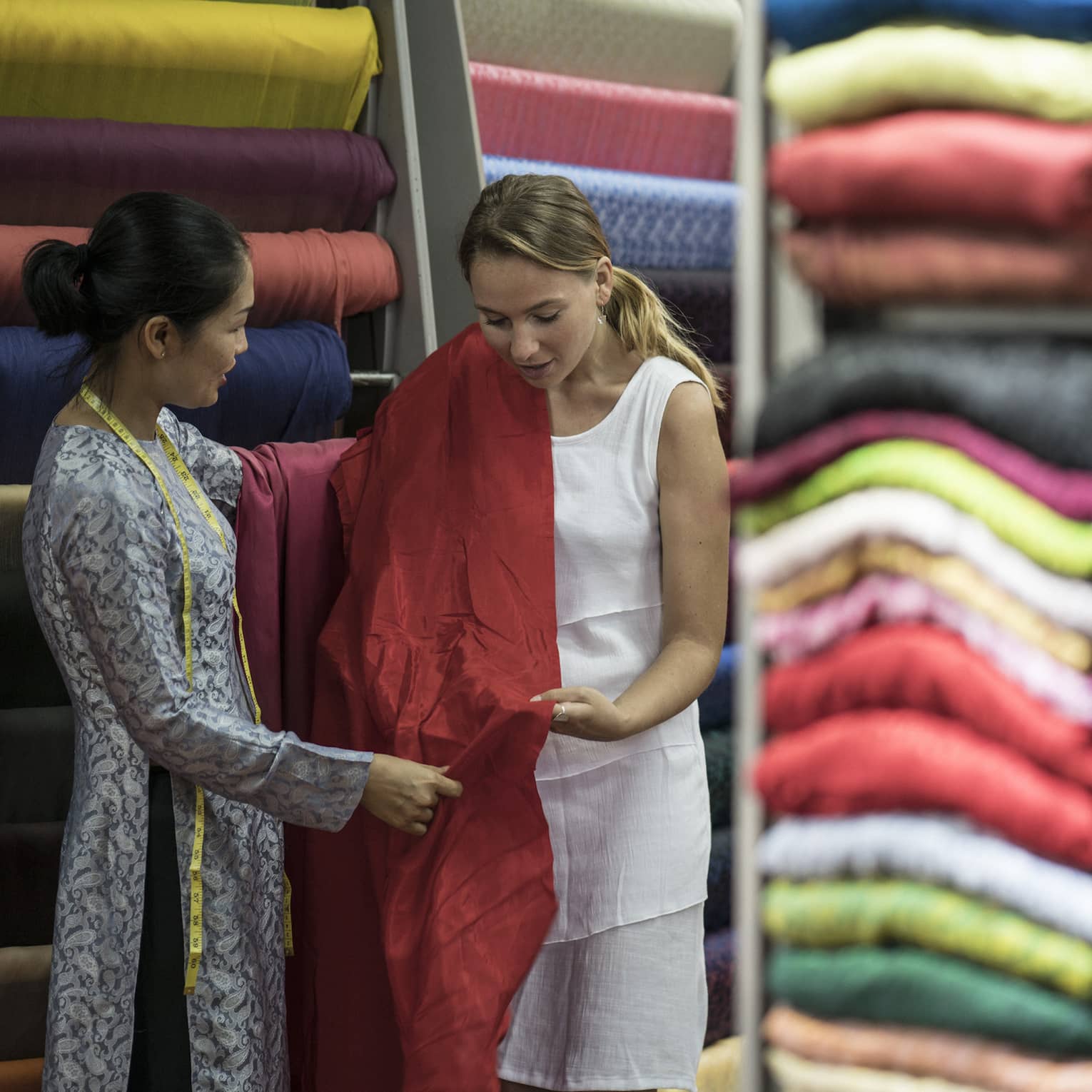 Two women standing in a room of fabric.