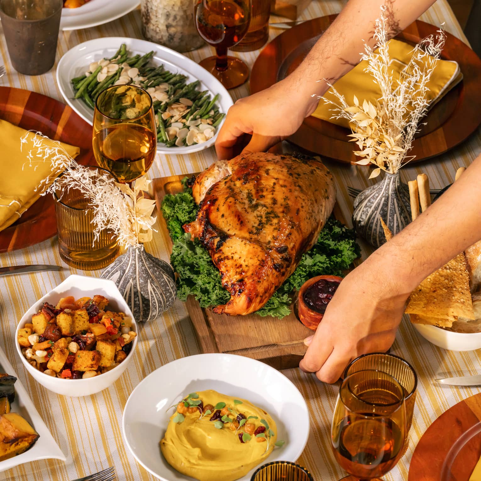 Whole roasted turkey being placed in the centre of a table filled with holiday dishes