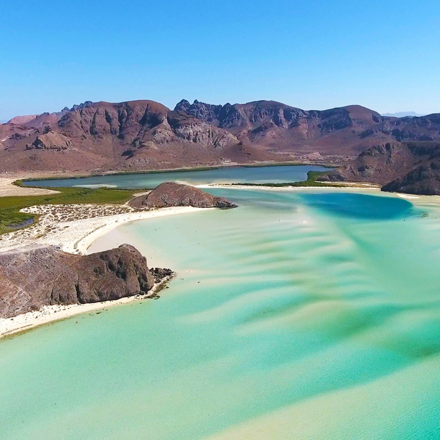 A beach shore with bright blue green water.