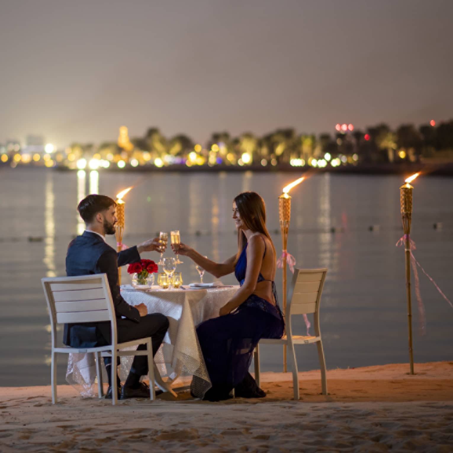 A couple dines along the gulf with the Doha city skyline in the background.
