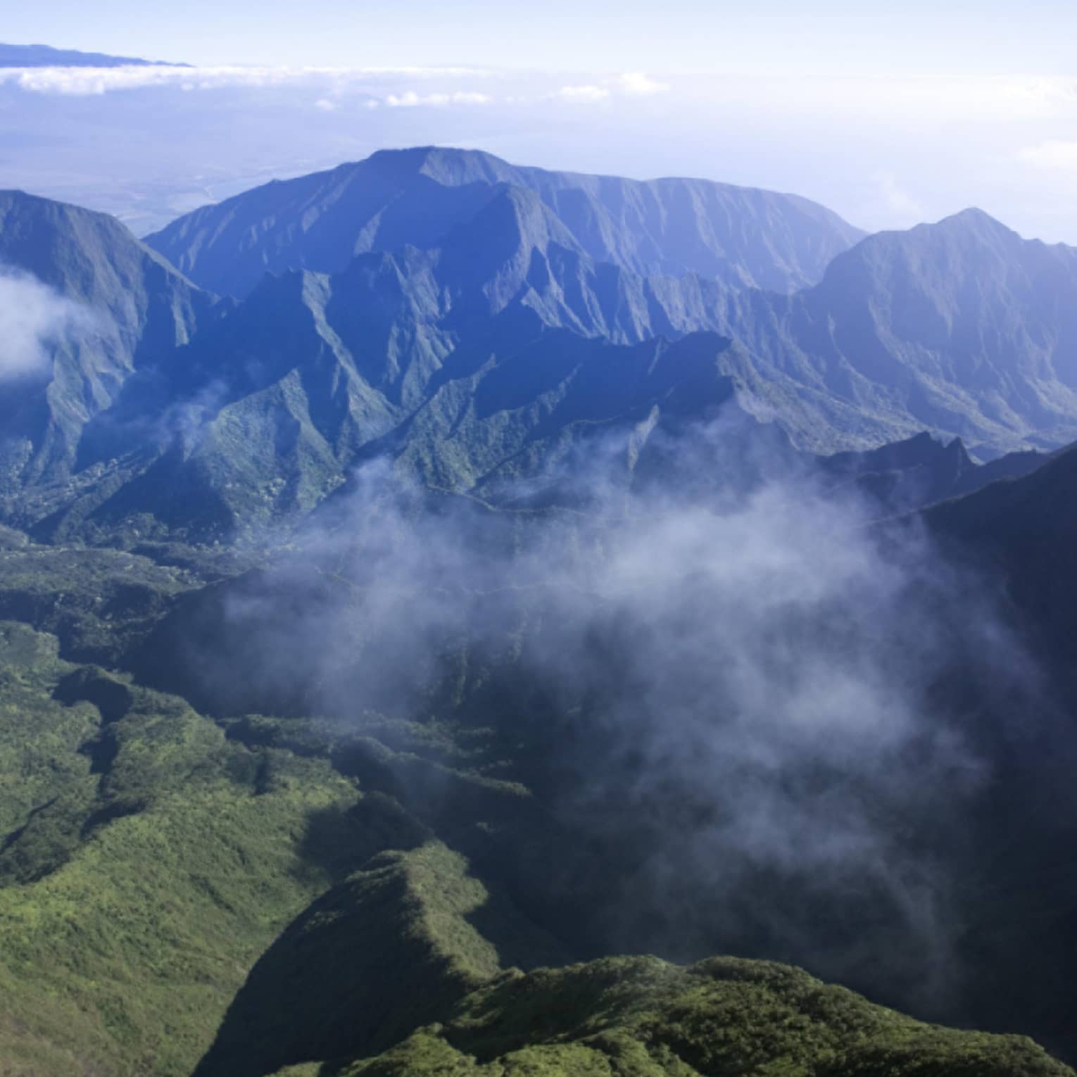 Clouds hover over green volcanic mountains