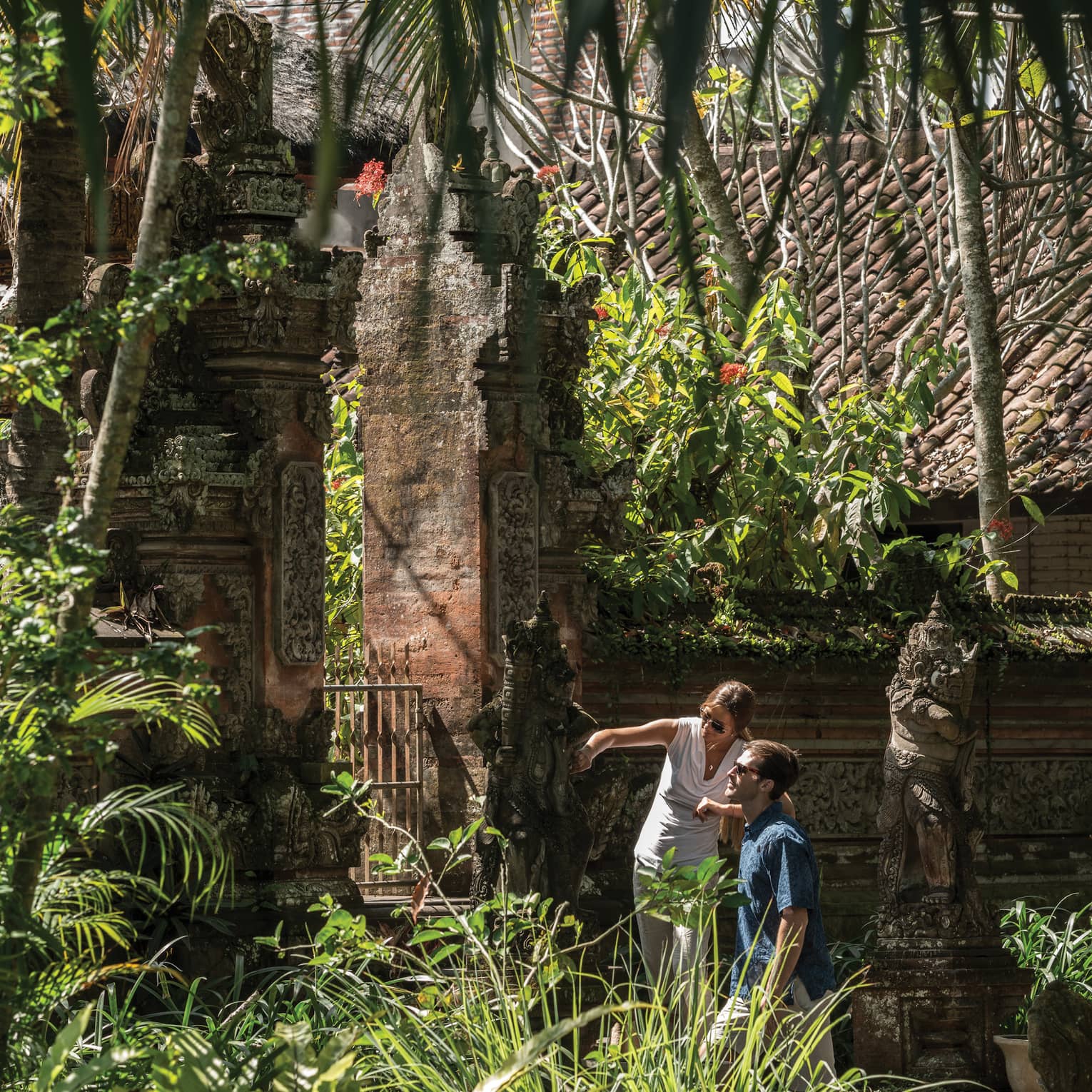 Gusts exploring decorative statues surrounding a temple in Bali