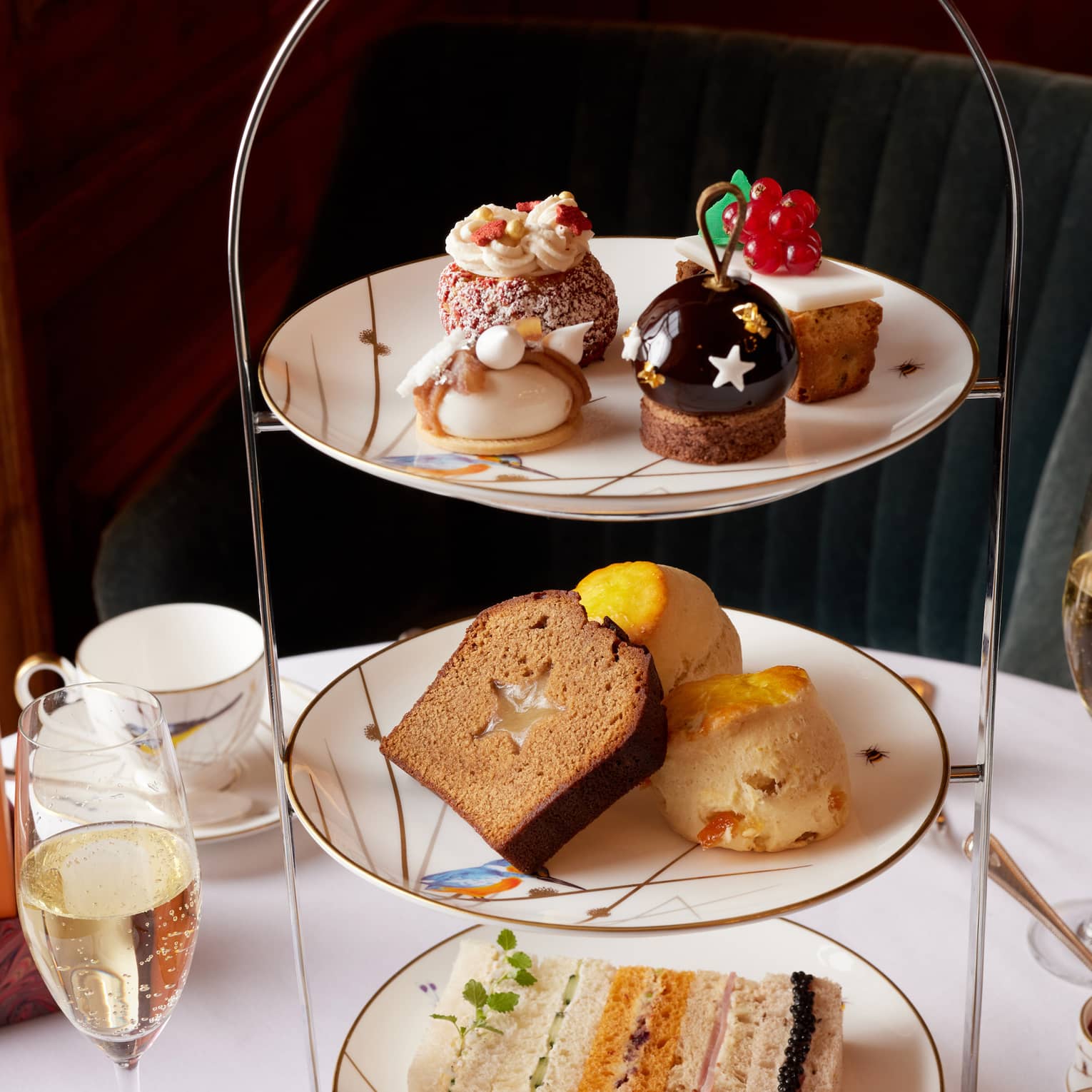 Elegant tea stand filled with holiday treats, cakes and sandwiches, along with champagne flutes