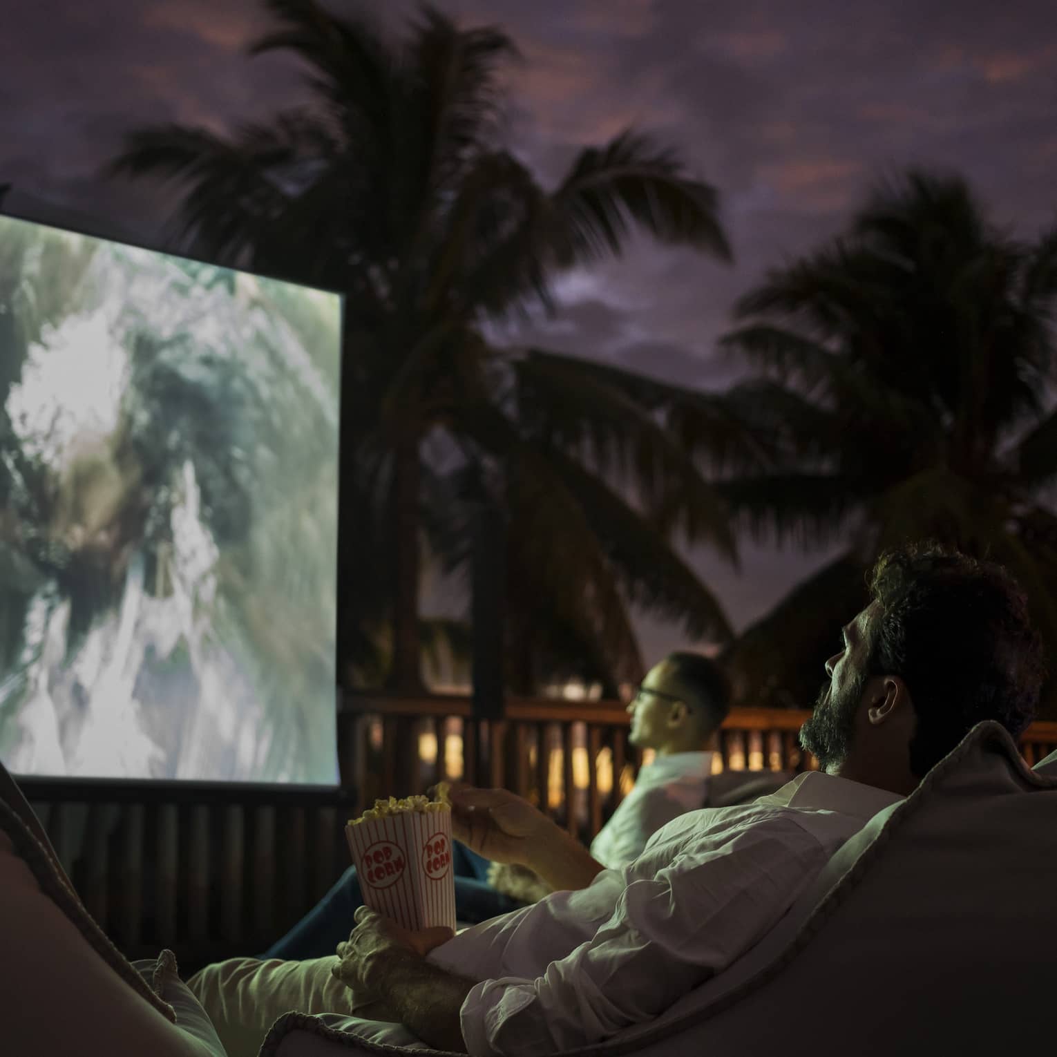 Group of people sit on bean bags with popcorn watching movie under the stars