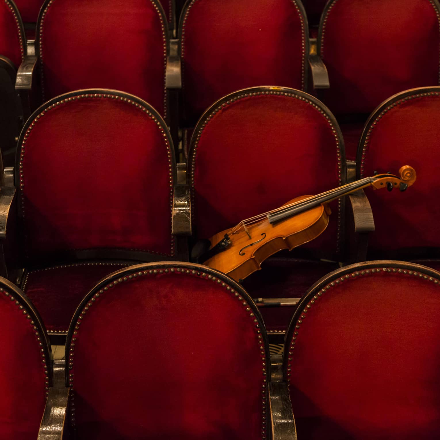 Red theatre chairs with a violin resting on one.