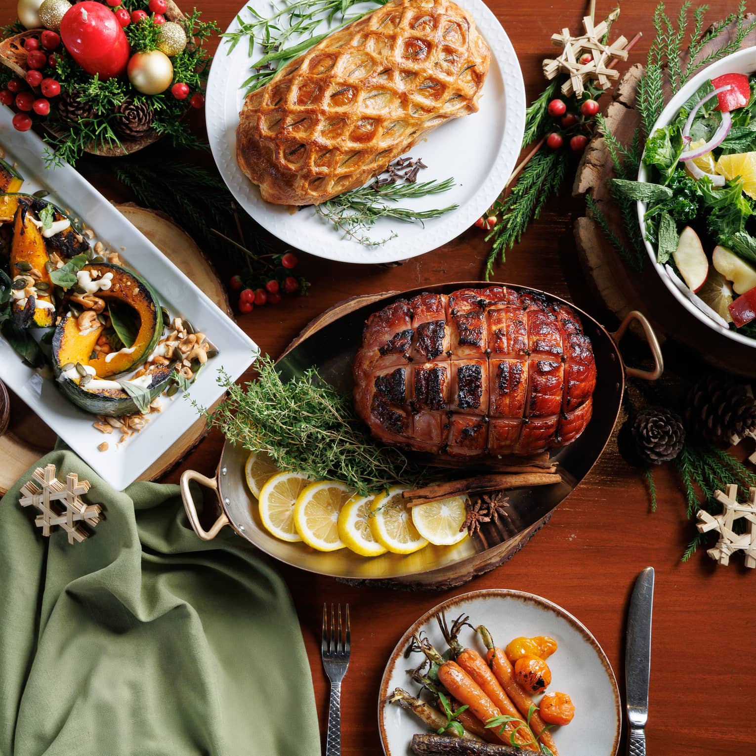 Baked ham, bowl of salad, sliced melons and more fill a table set for a Christmas meal