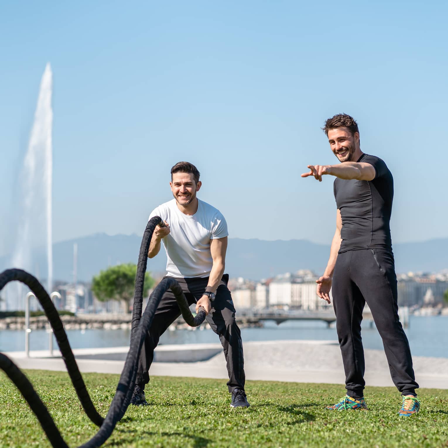 Man working out with ropes with guidance of trainer at Lake Geneva grassy shore