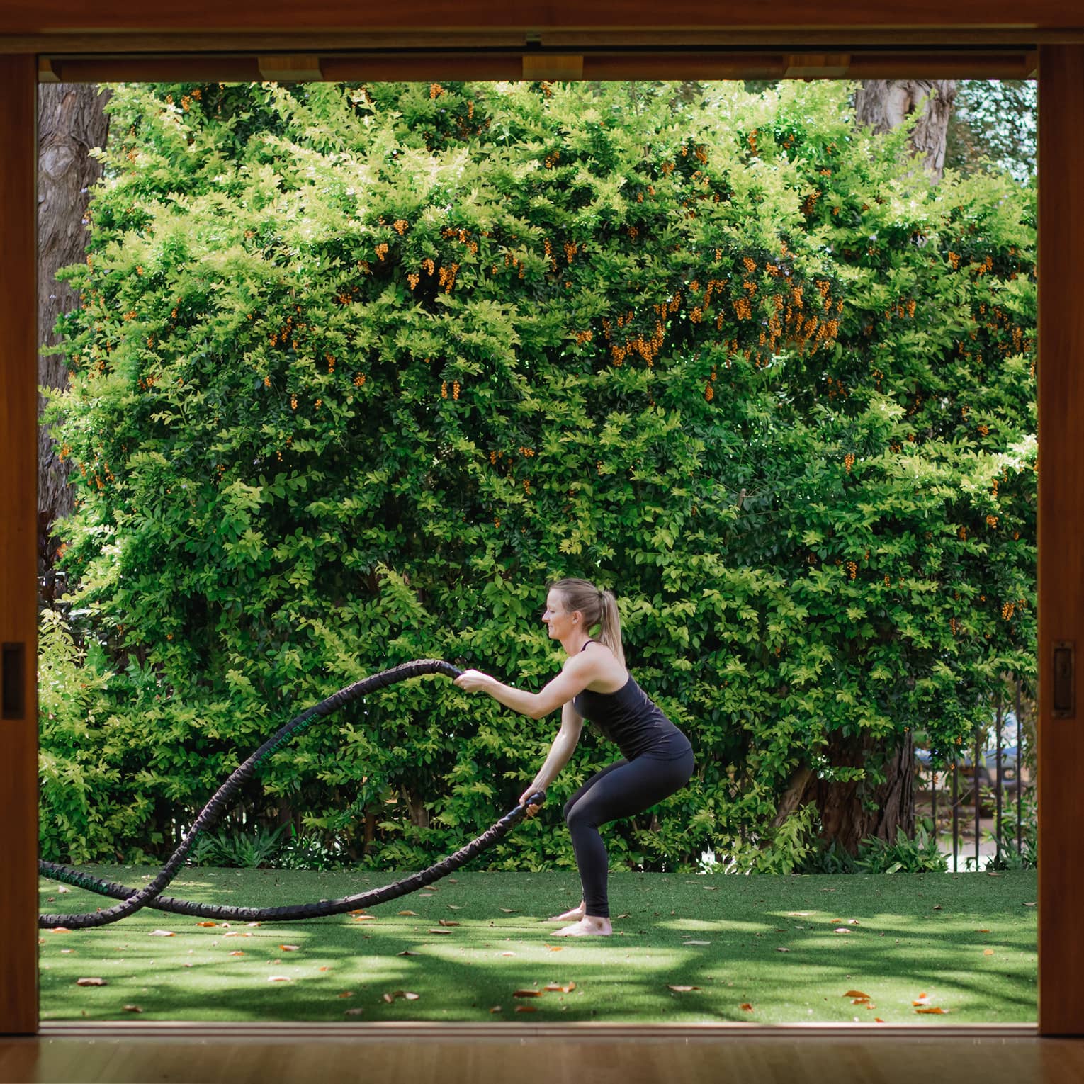 A woman does rope exercise outside on grass
