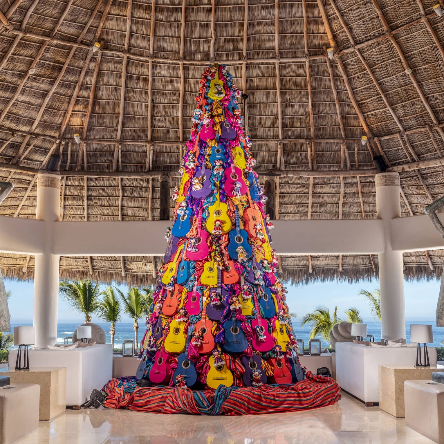 A Christmas tree made of colourful guitars inn a lobby area.