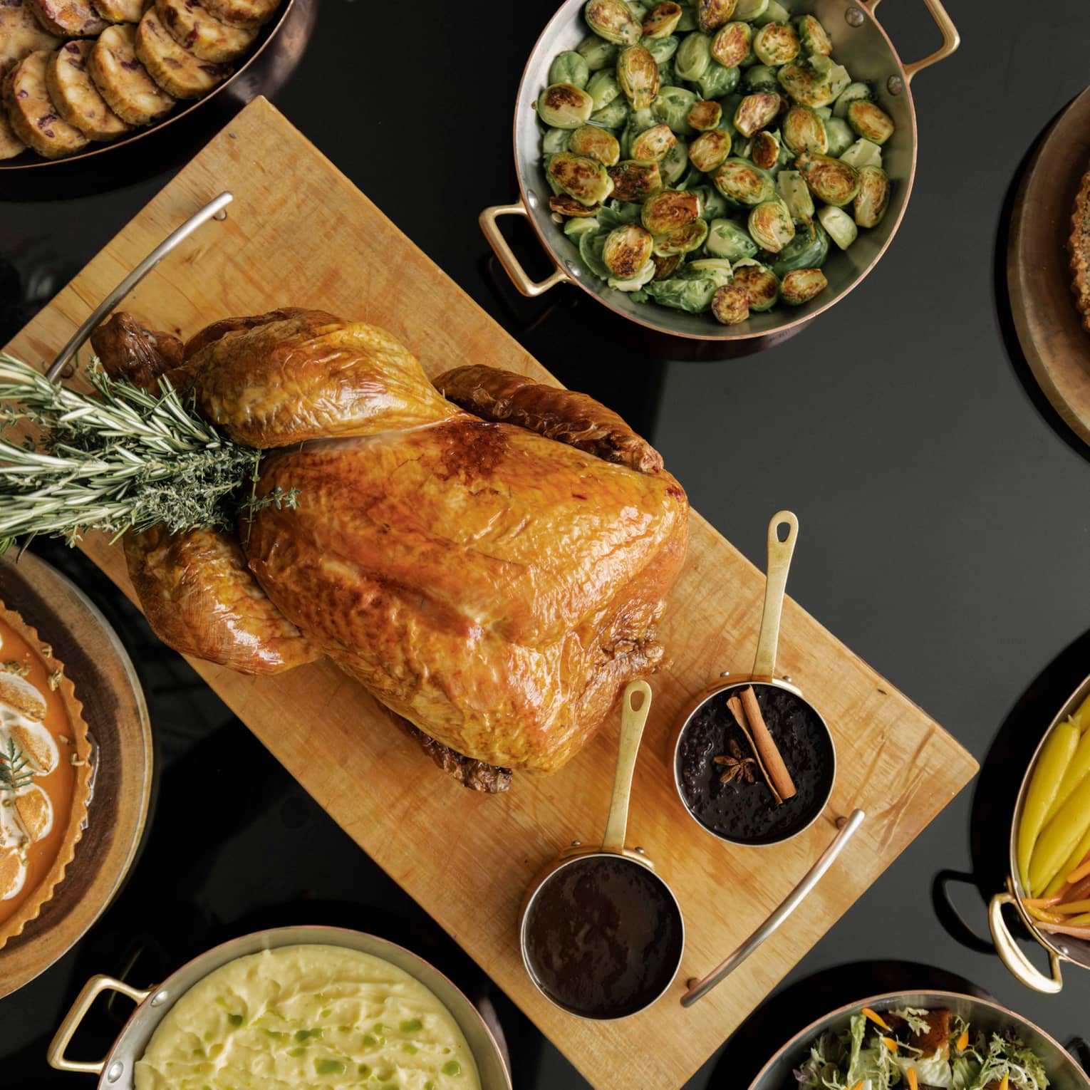 Table set with a roasted turkey, Brussels sprouts, sliced carrots and various other dishes for a holiday meal,Table set with a roasted turkey, Brussels sprouts, clived carrots and various other dishes for a holiday meal