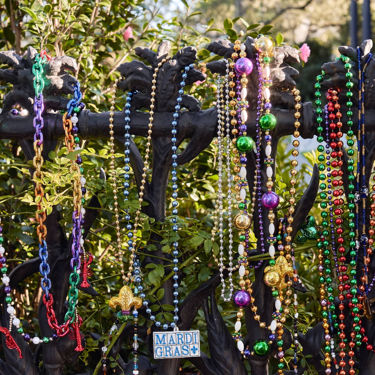 Strands of colourful Mardi Gras beads hanging on a wrought iron post