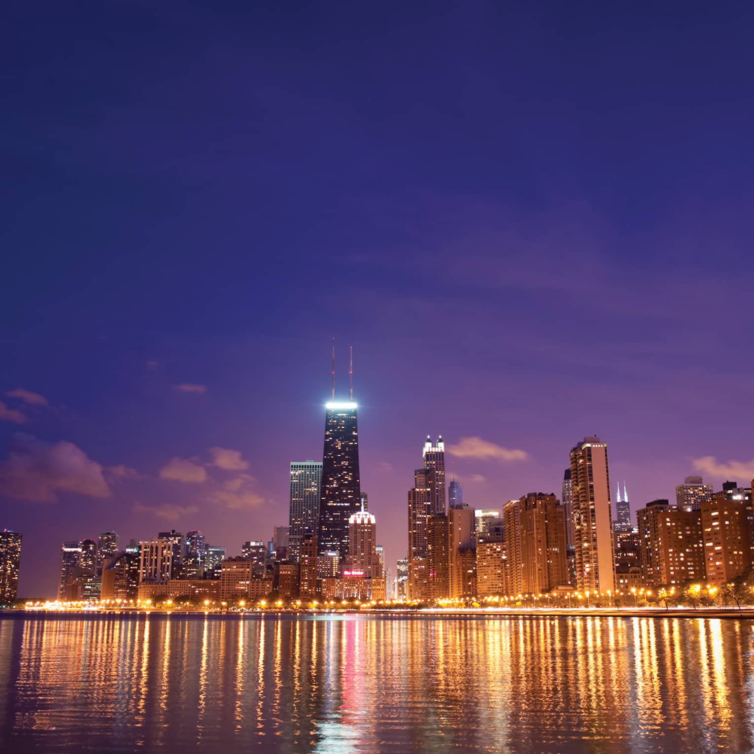 Chicago skyline at night on water with skyscrapers light up with lights