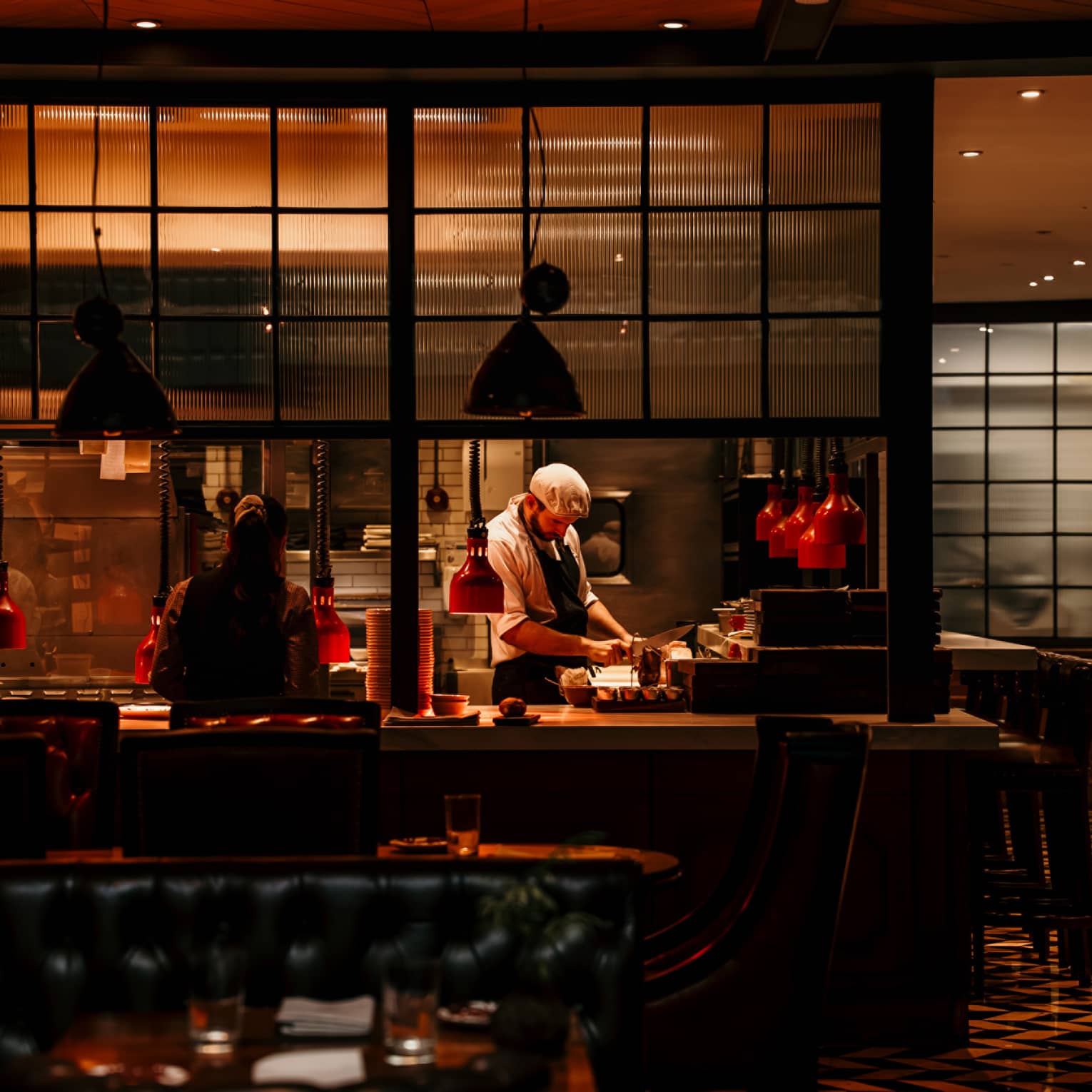 Chefs preparing food in a dimly lit dining room