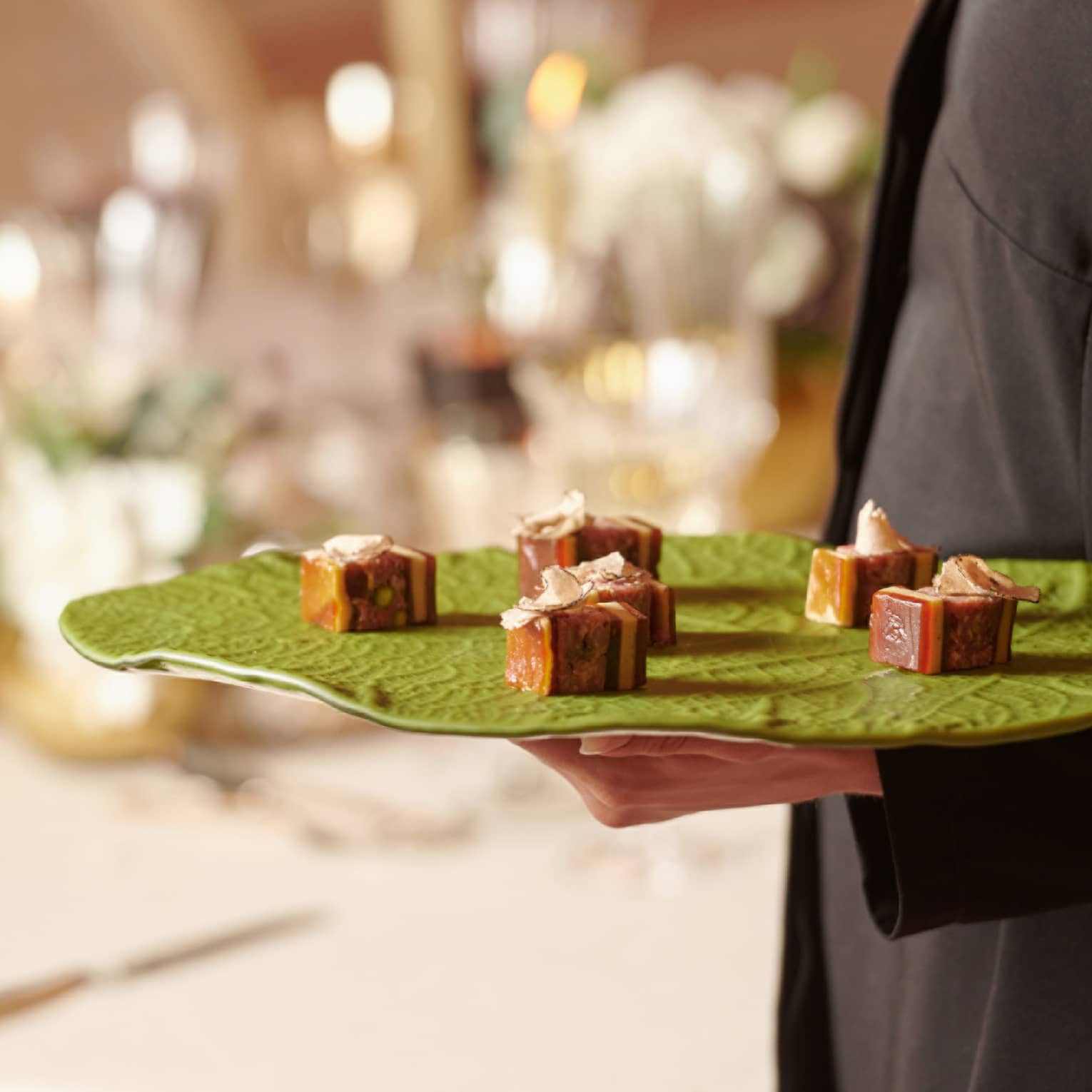 A team member carrying a tray of small foods.