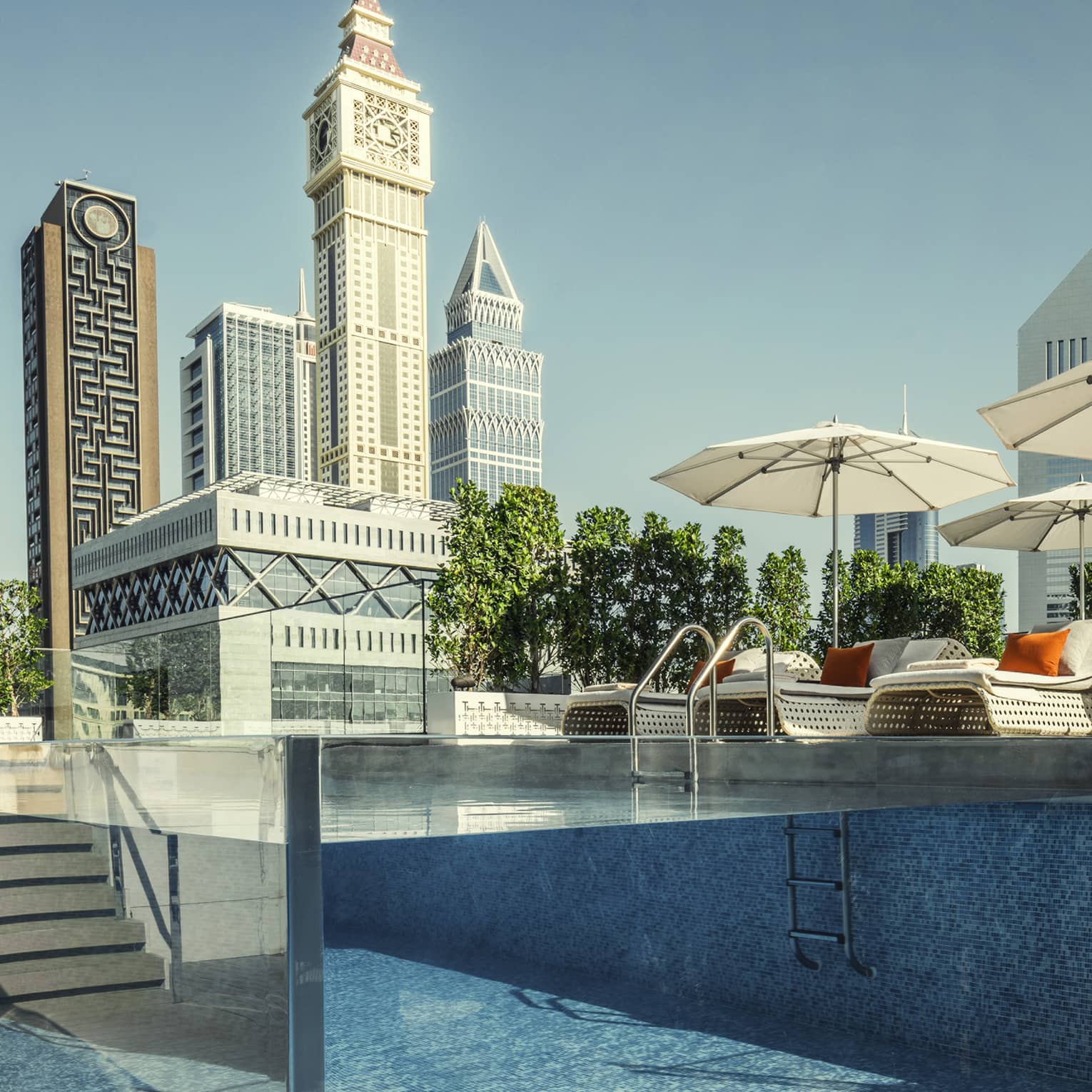 Raised glass plunge pool by stairs on patio deck, lounge chairs, umbrella