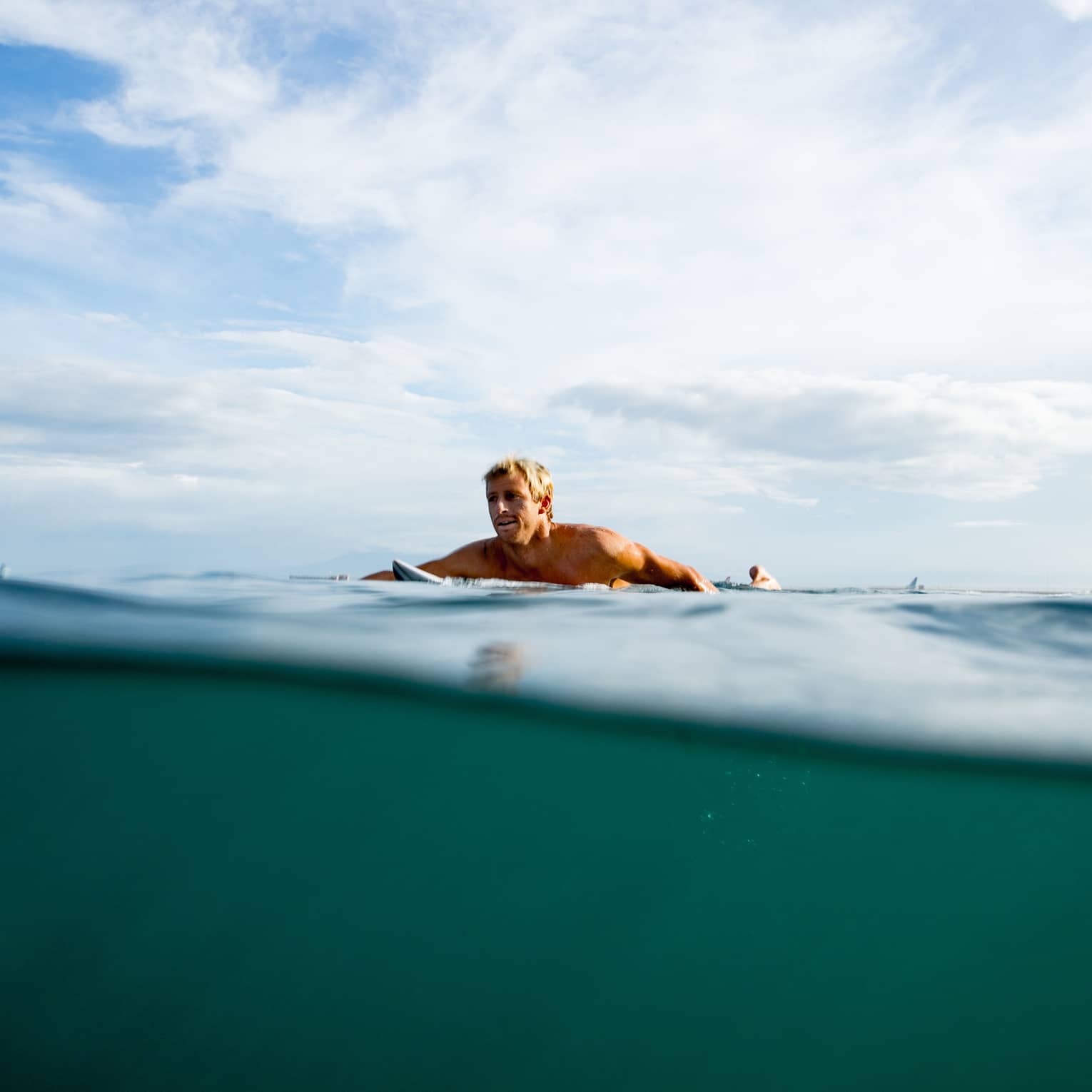 A guest swims out to surf on the water in Bali