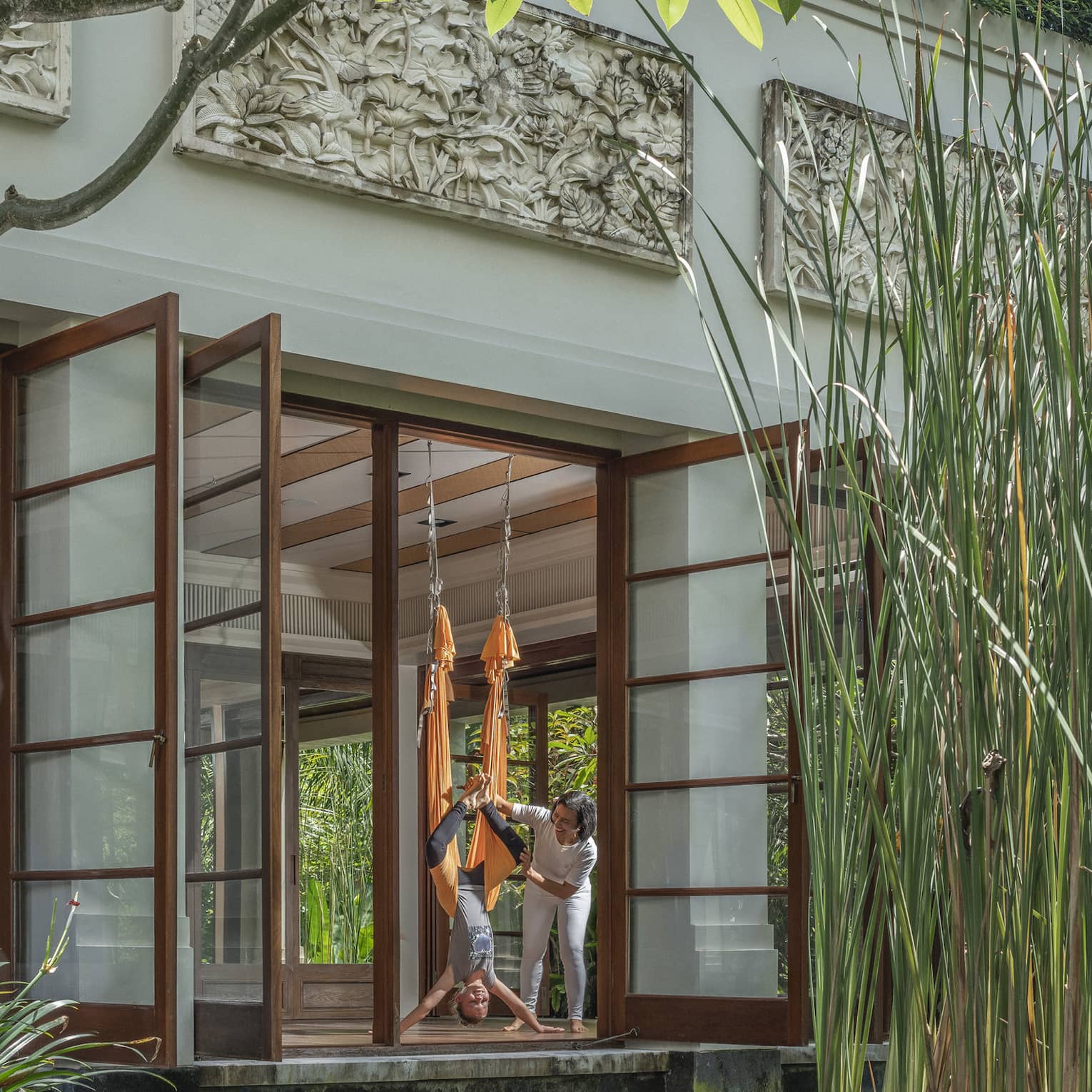 Instructor guides woman in hammock during AntiGravity Yoga session