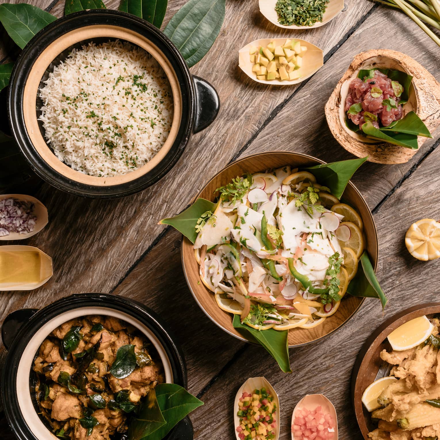 Aerial view of rustic wood table with bowls of gourmet rice, salads and entrees