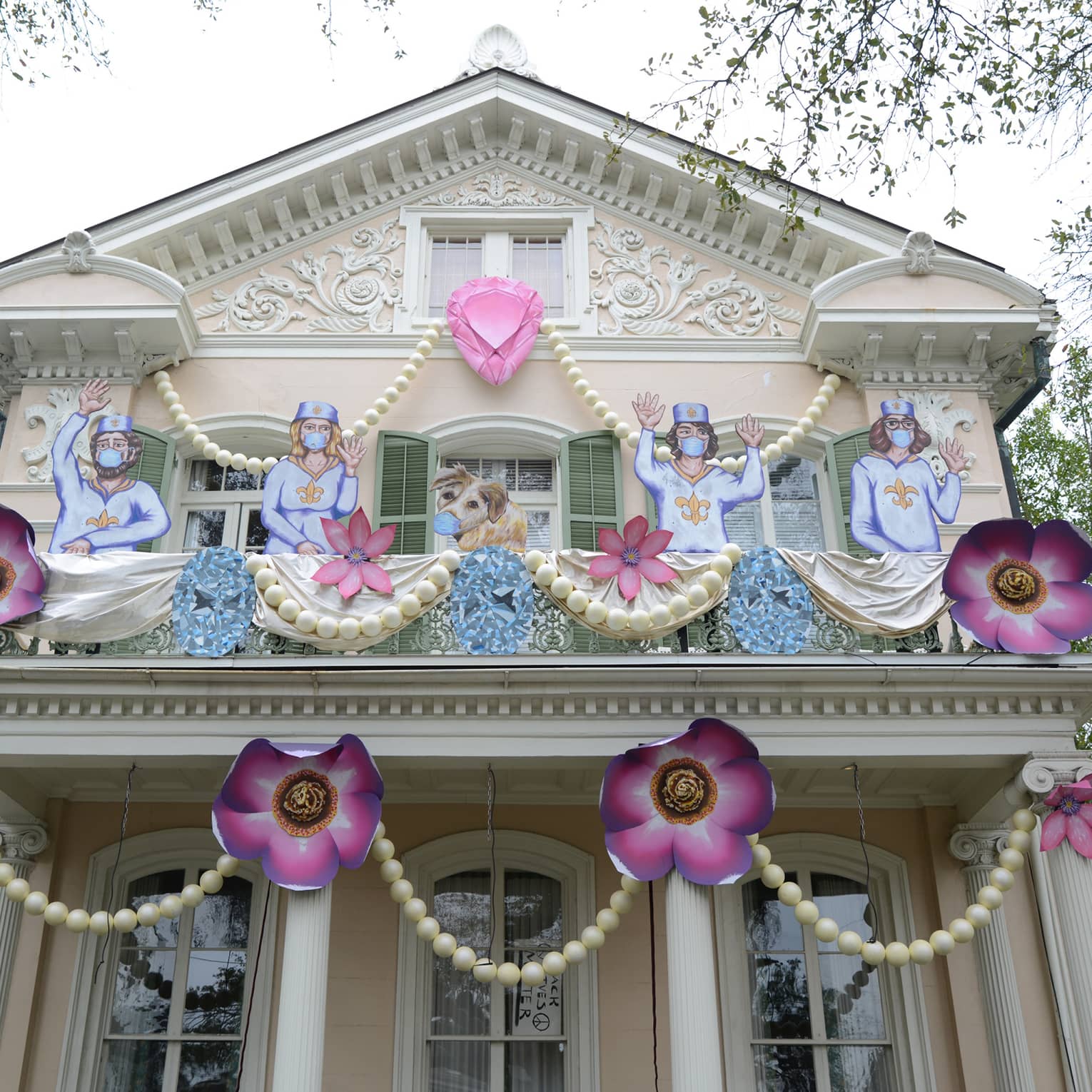 Cream-coloured Gothic two-storey house in New Orleans with pink flower garland and Mardi Gras decorations