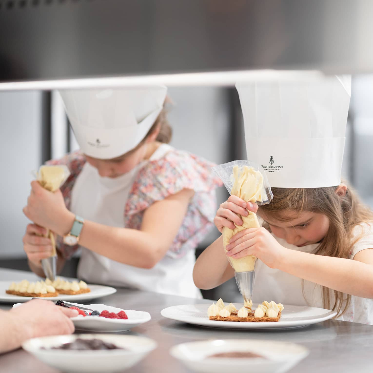 Children icing cooking while wearing chef hats.