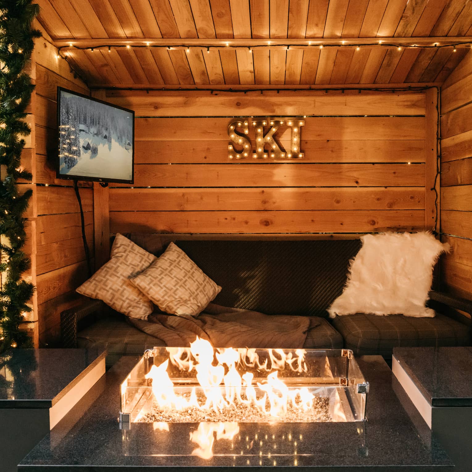 A cozy winter chalet with a fire and couch to rest on.
