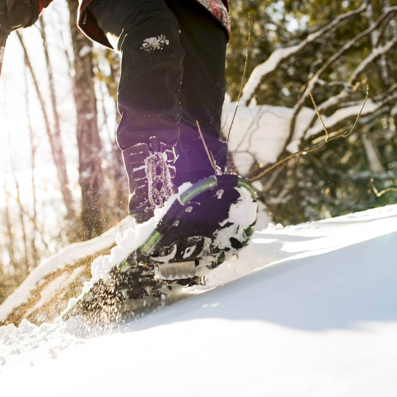 A person walking on snow using snow shoes and poles to help them walk.