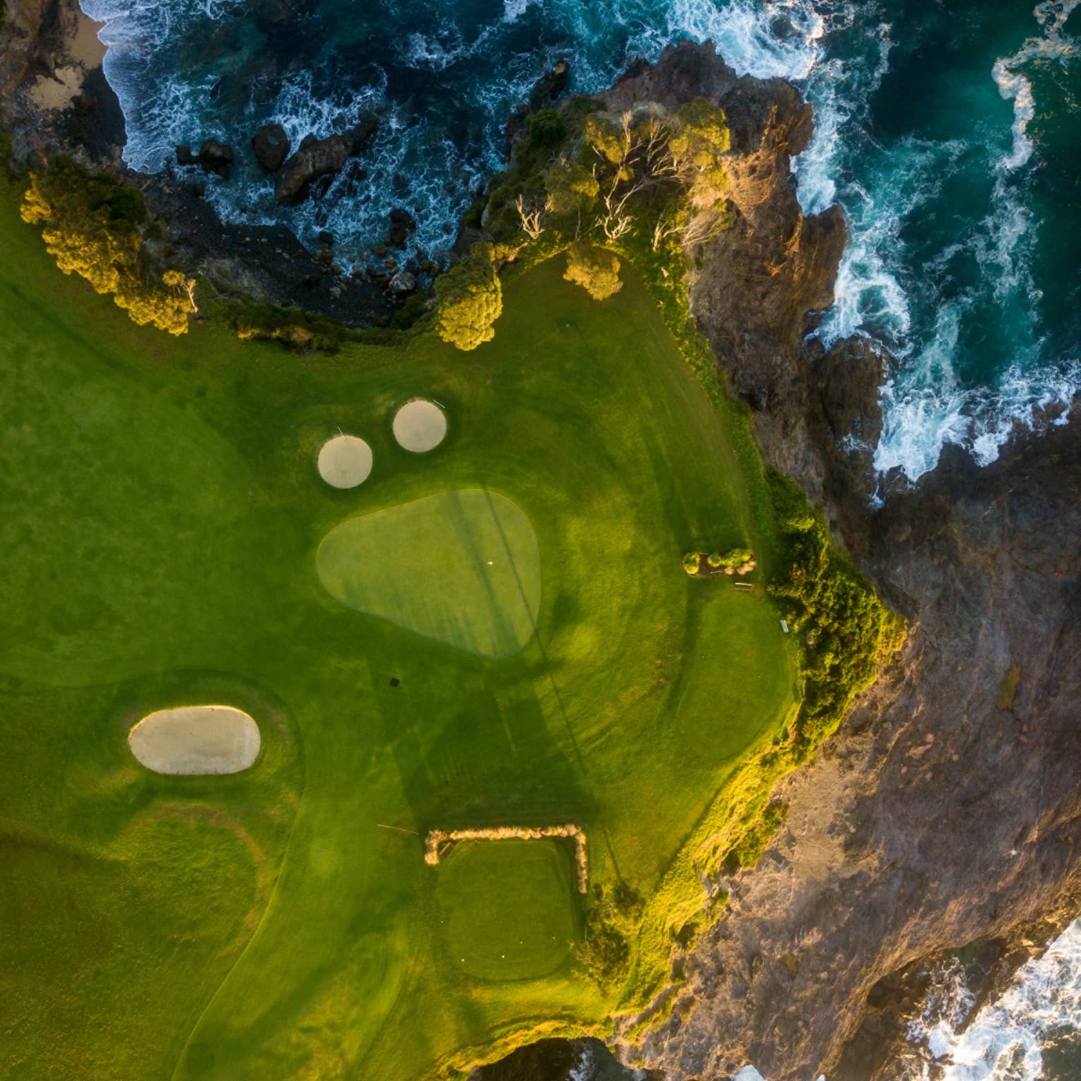 Aerial view of coastal golf course with craggy shores