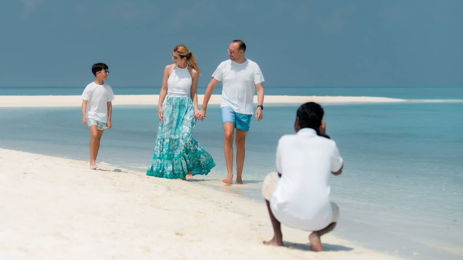 A photographer captures a photo of a family walking along a beach