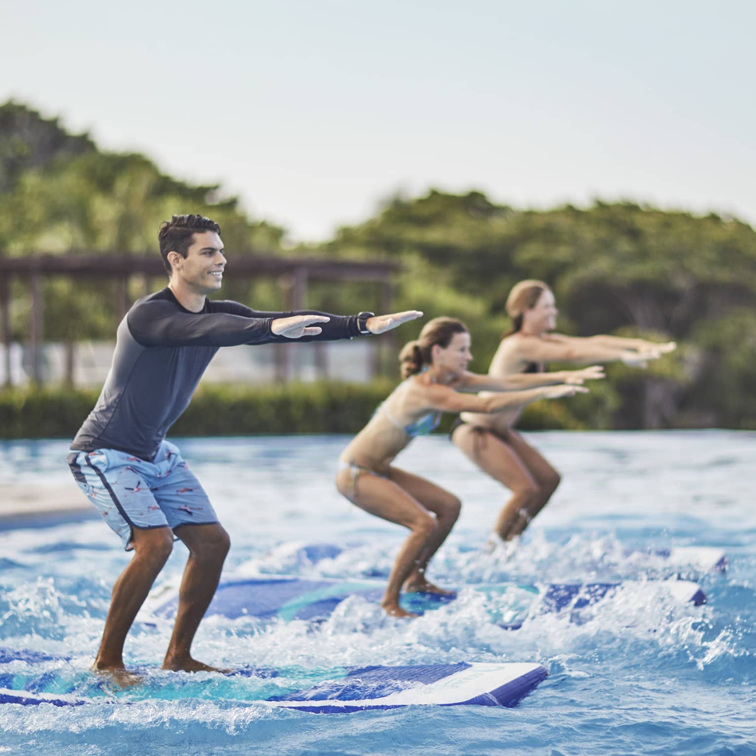 Two guests being instructed how to stand up on surf boards