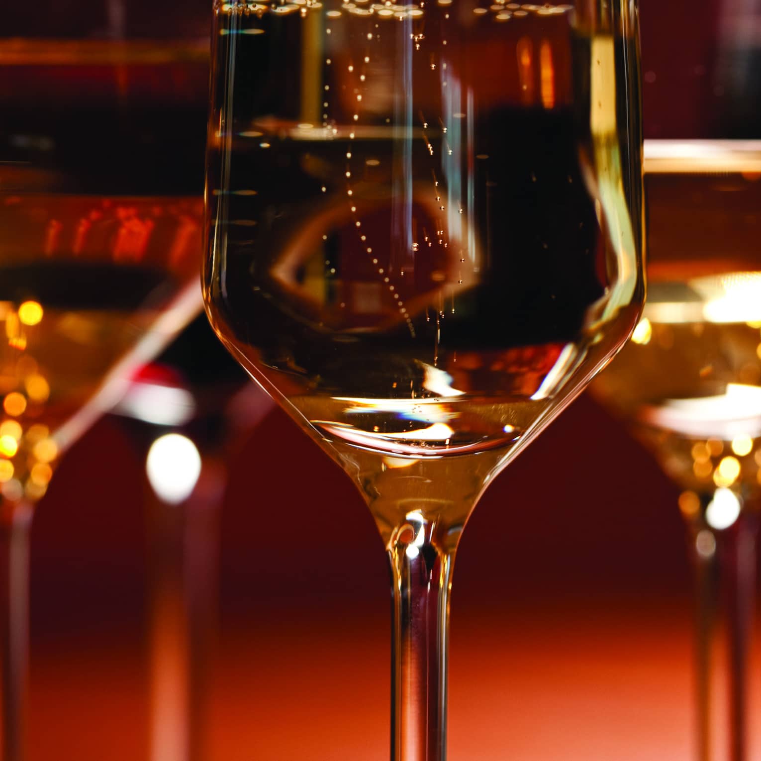 Up close shot of three crystal wine glasses with a red background