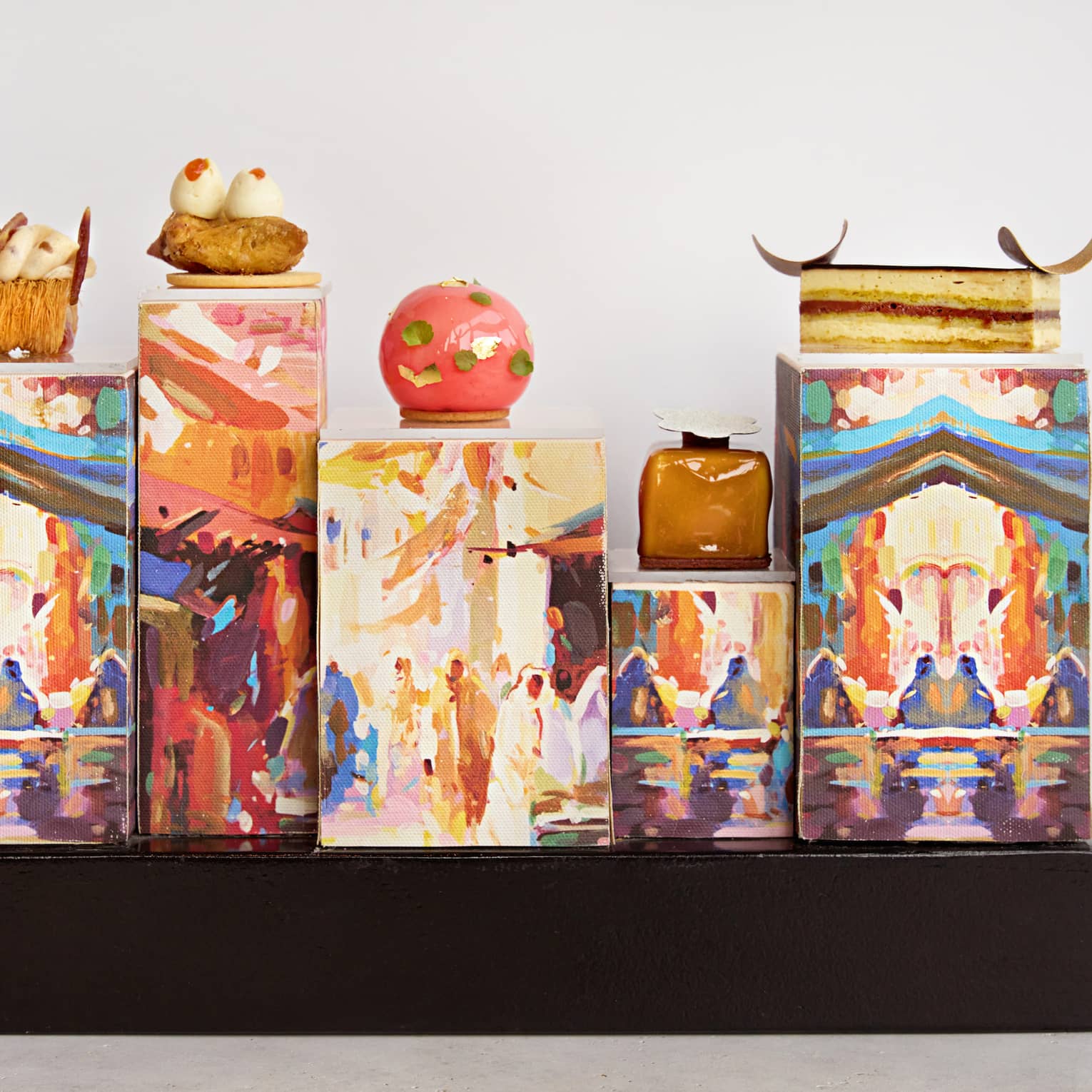 Small pastries placed on top of rectangles decorated with works of art