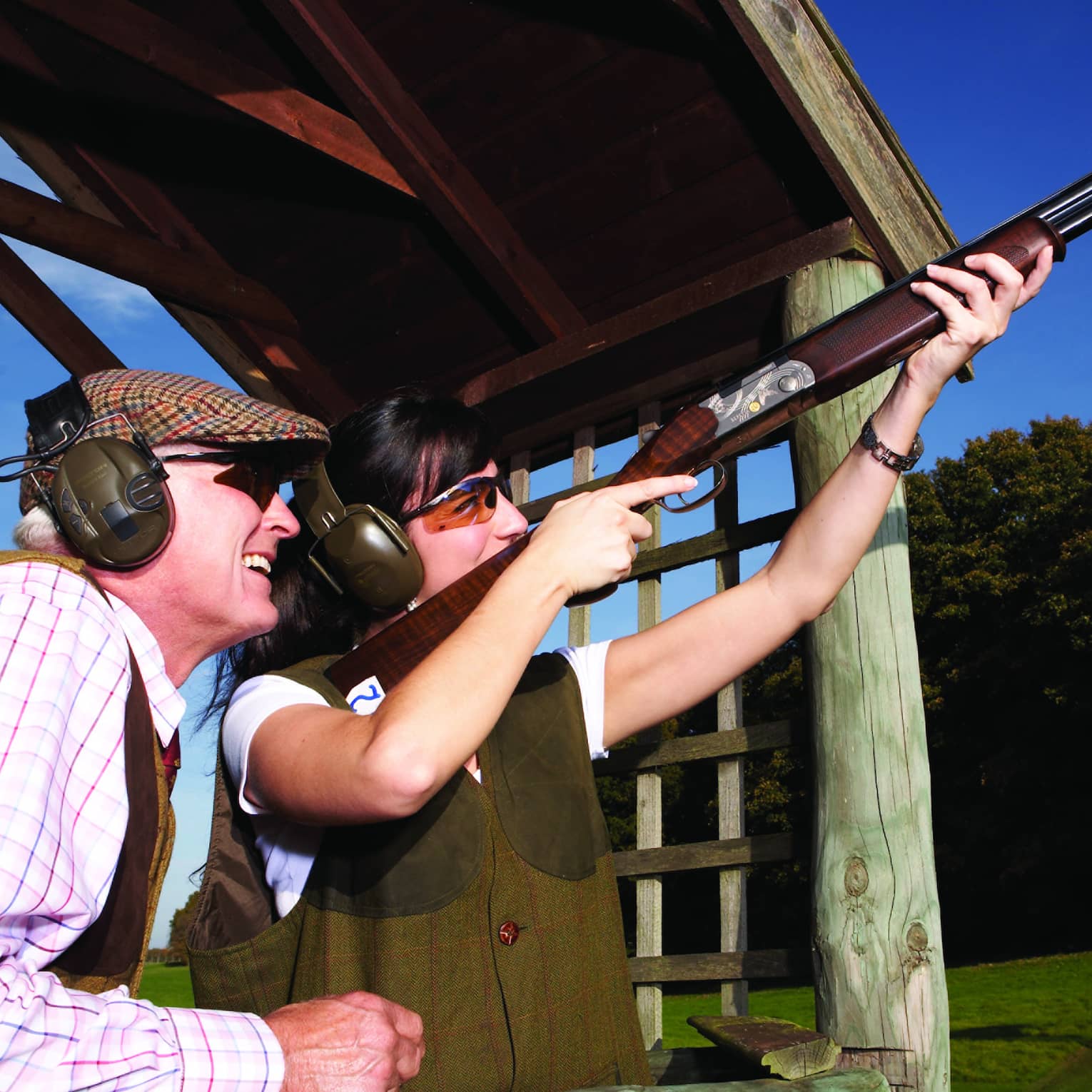 A man and woman shooting clay pigeons outside