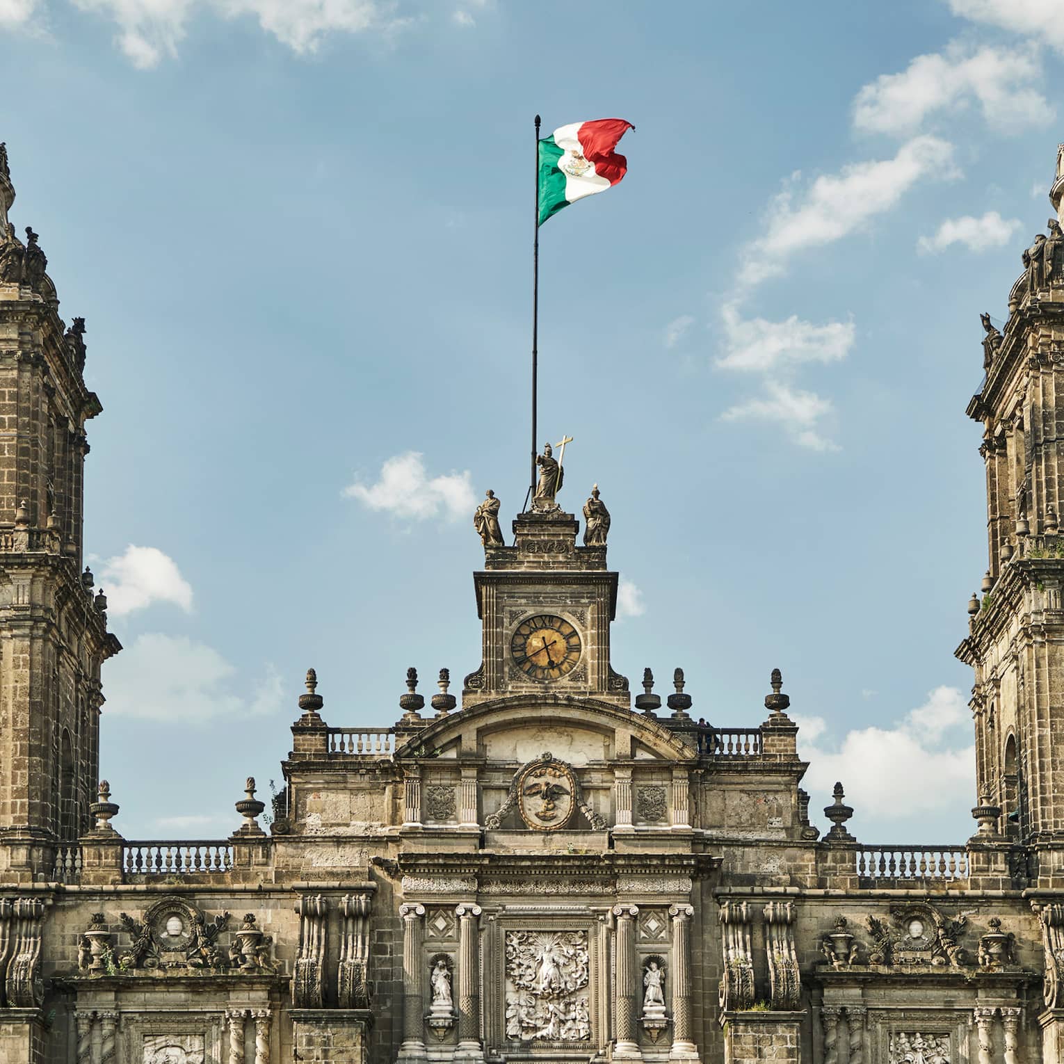 Historic Mexico City building, towers with flag against blue sky
