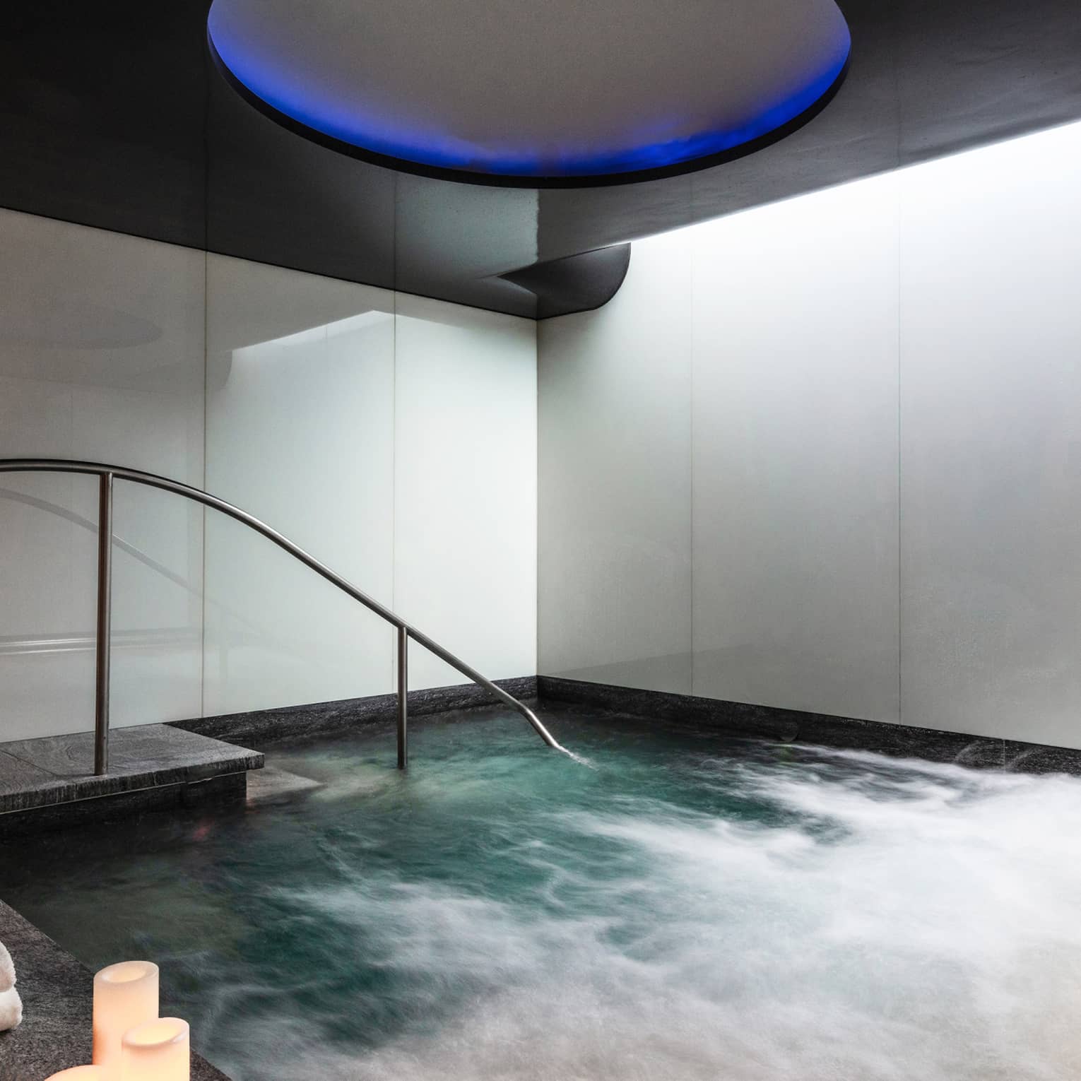 An indoor whirlpool with candle on the ledge.
