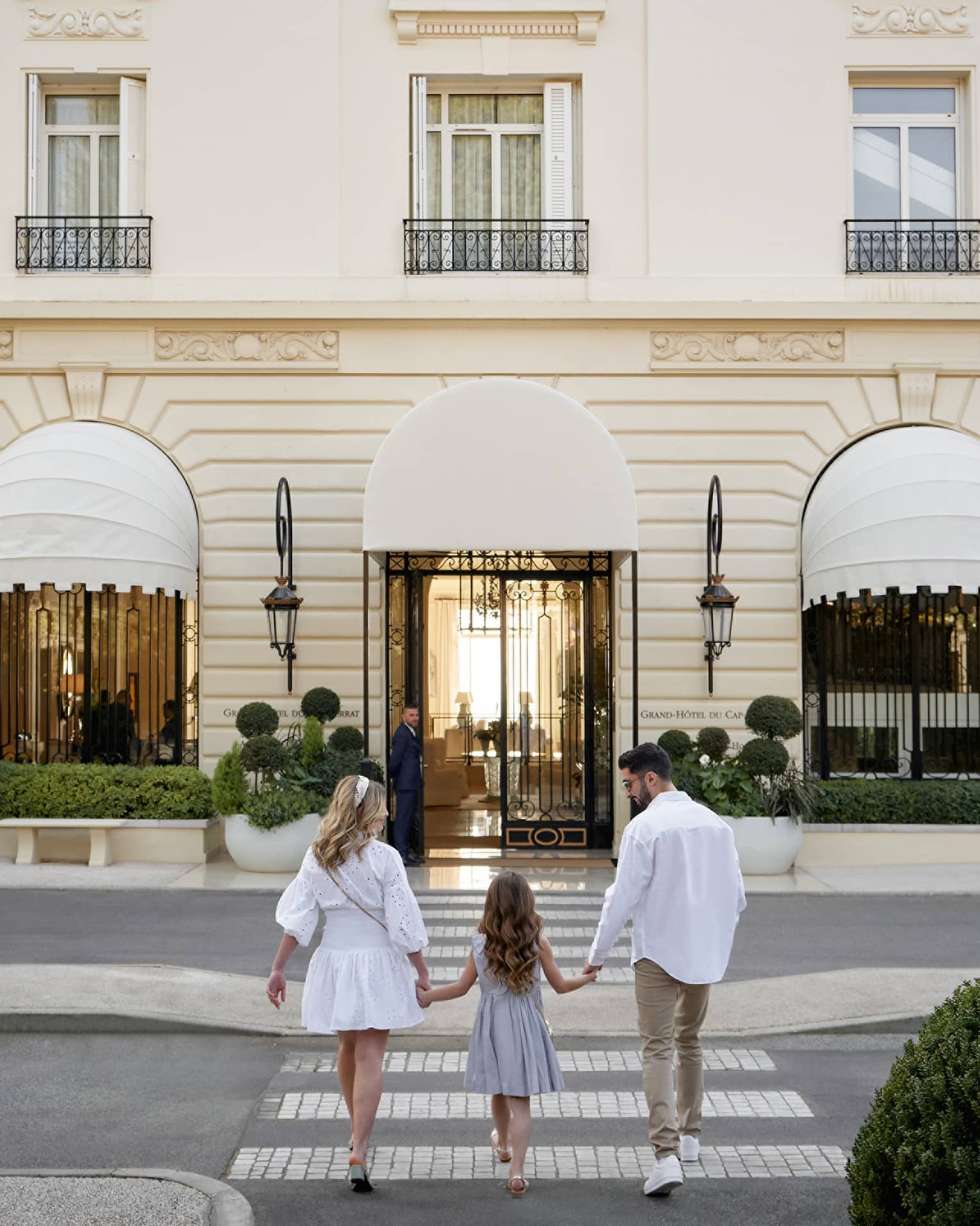 Family of three holding hands while walking toward the Grand-H�tel