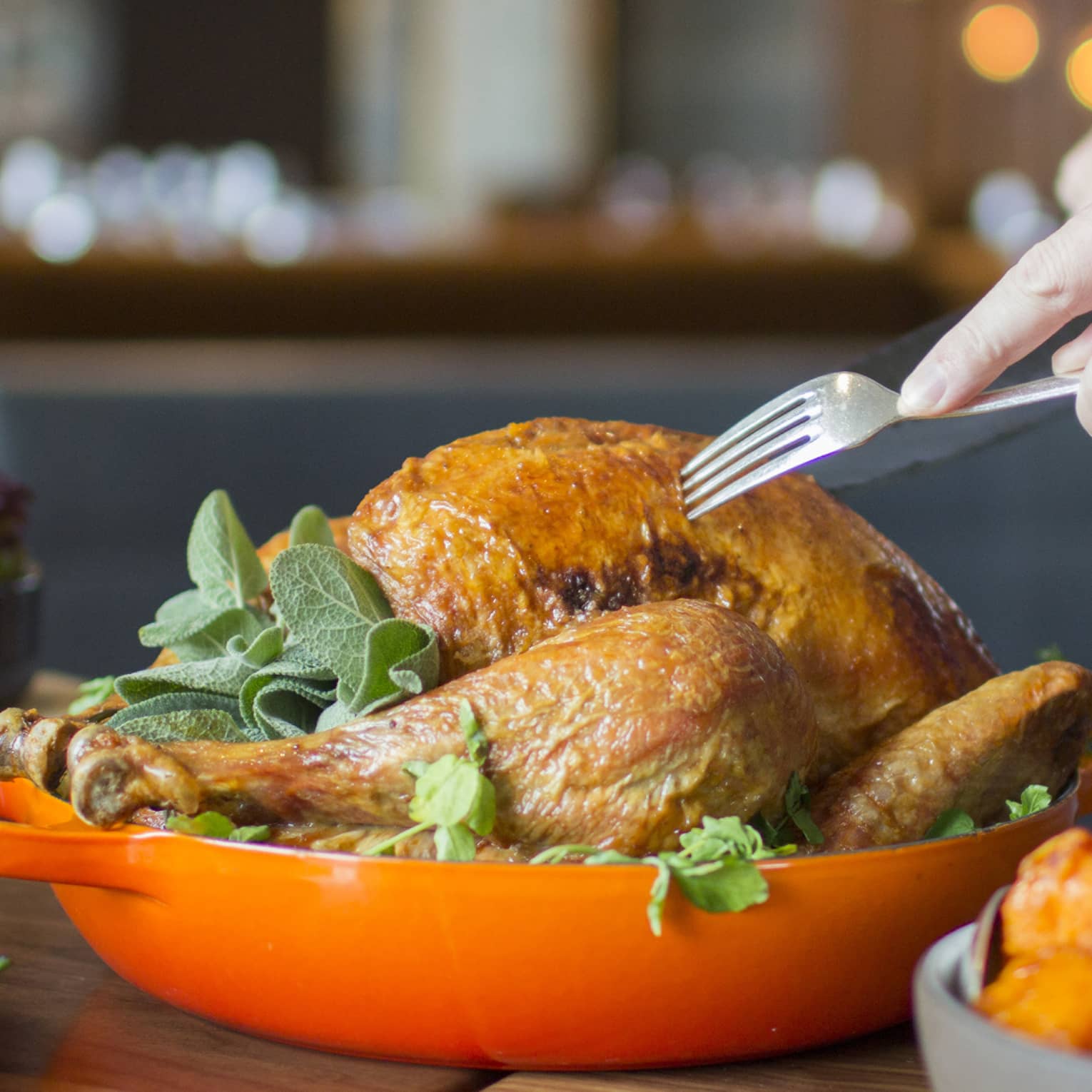 Thanksgiving turkey in orange dish being served by server holding fork