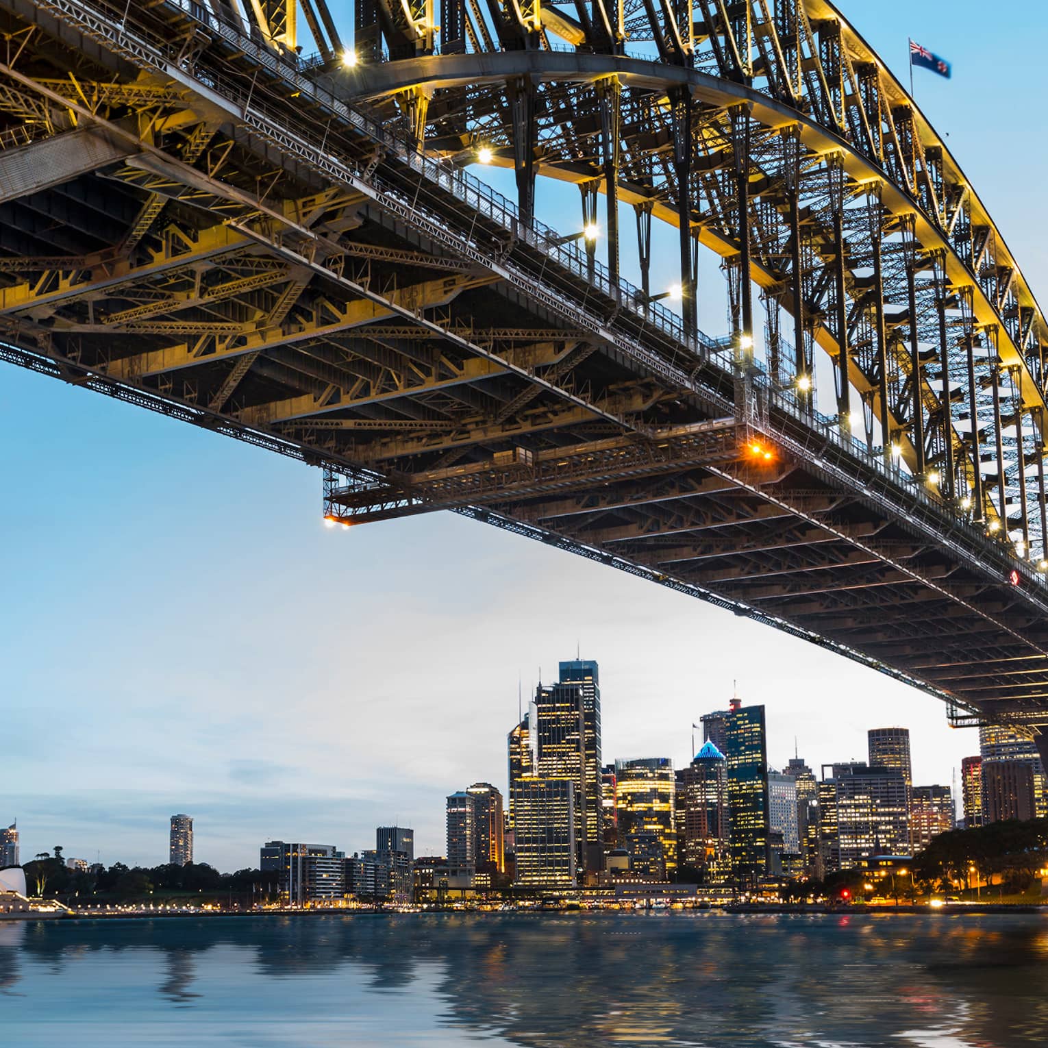 View from under bridge to Sydney waterfront skyline, lights at dusk