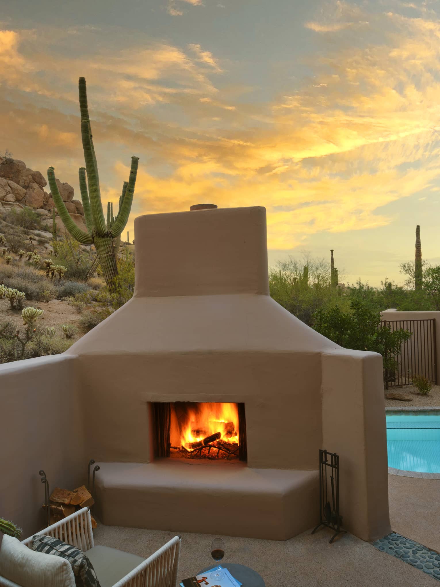 A pool beside a fire pit with a chair, surrounded by desert views