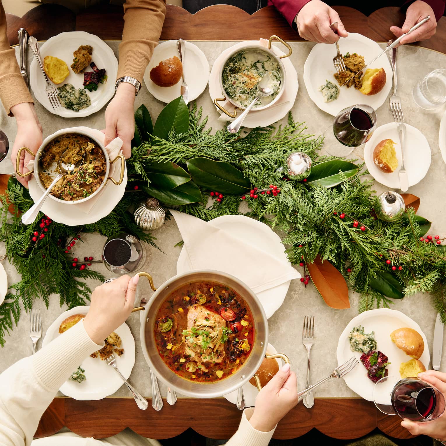 A large wood table and people sitting around with a variety of food.