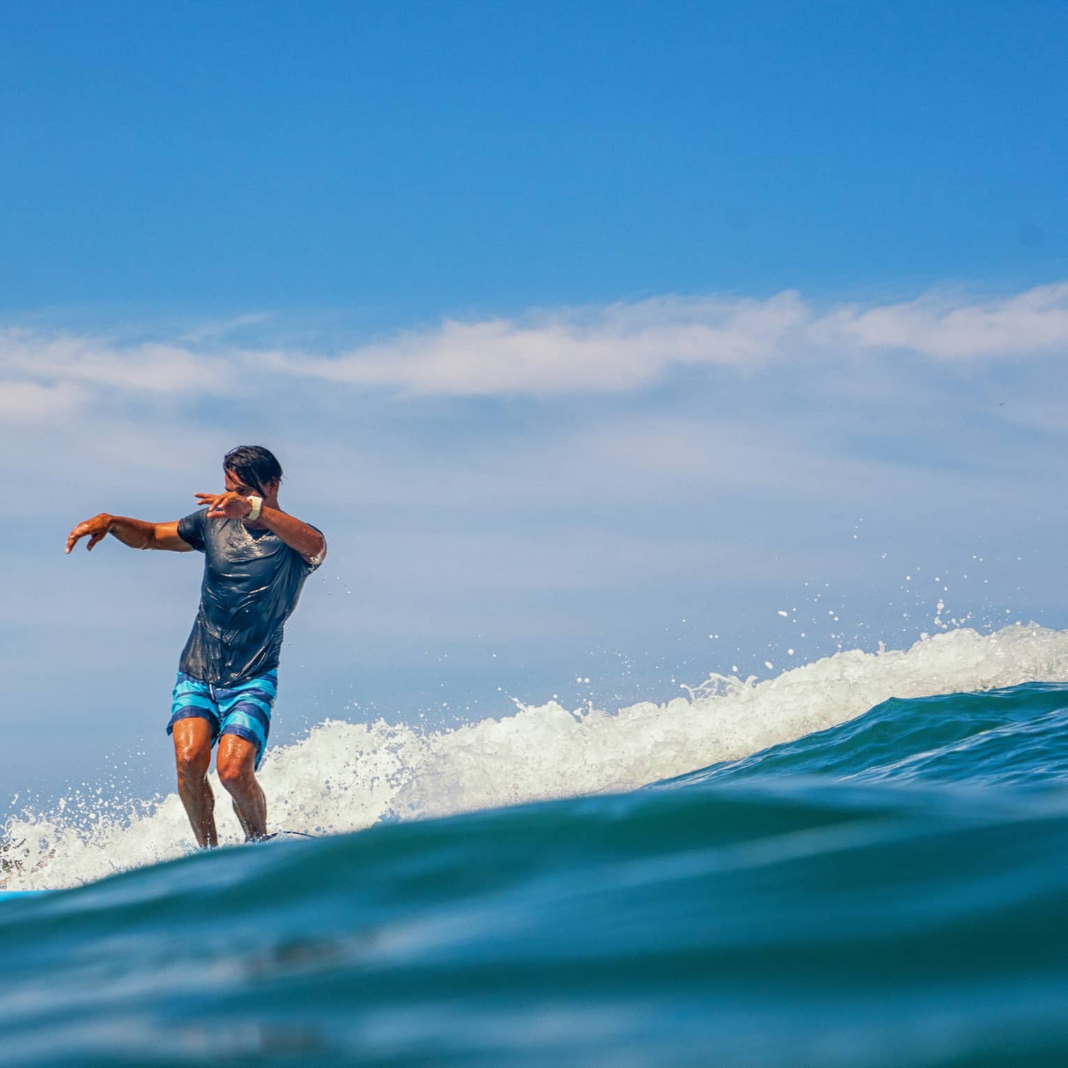 Person standing on a surf board on a wave in the ocean.