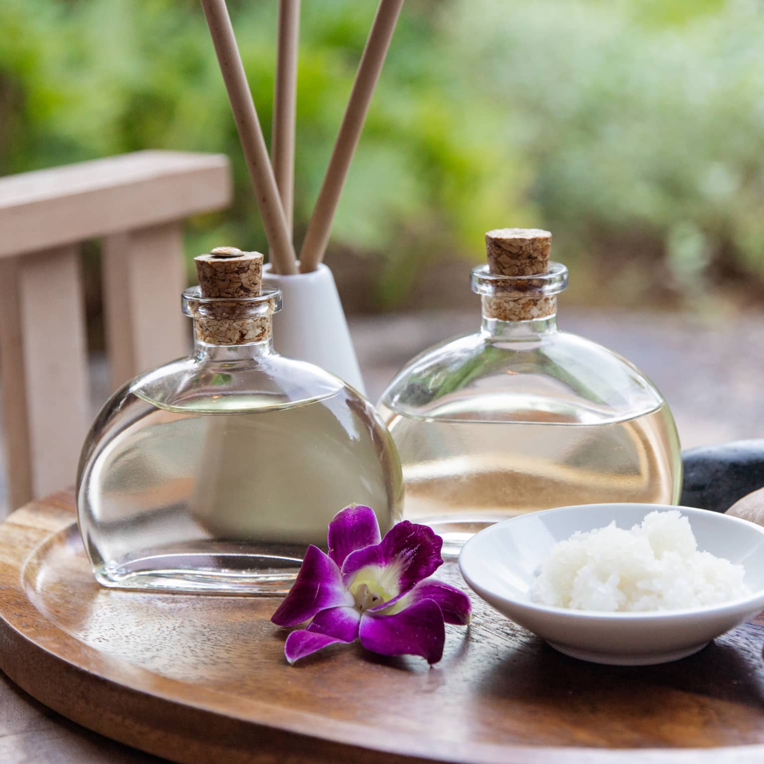 Spa oils and hot stones on wooden platter
