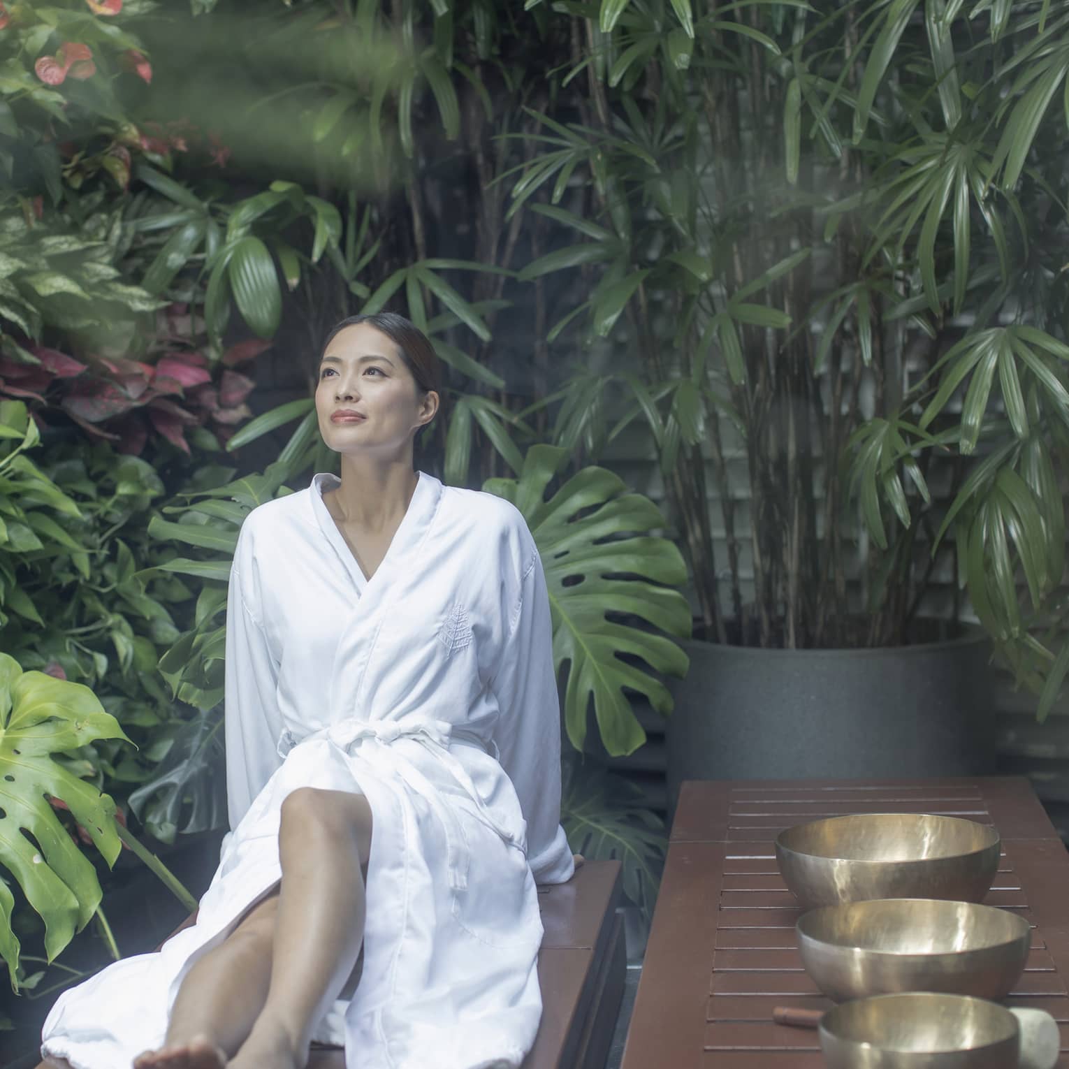 Woman wearing spa robe sits in garden