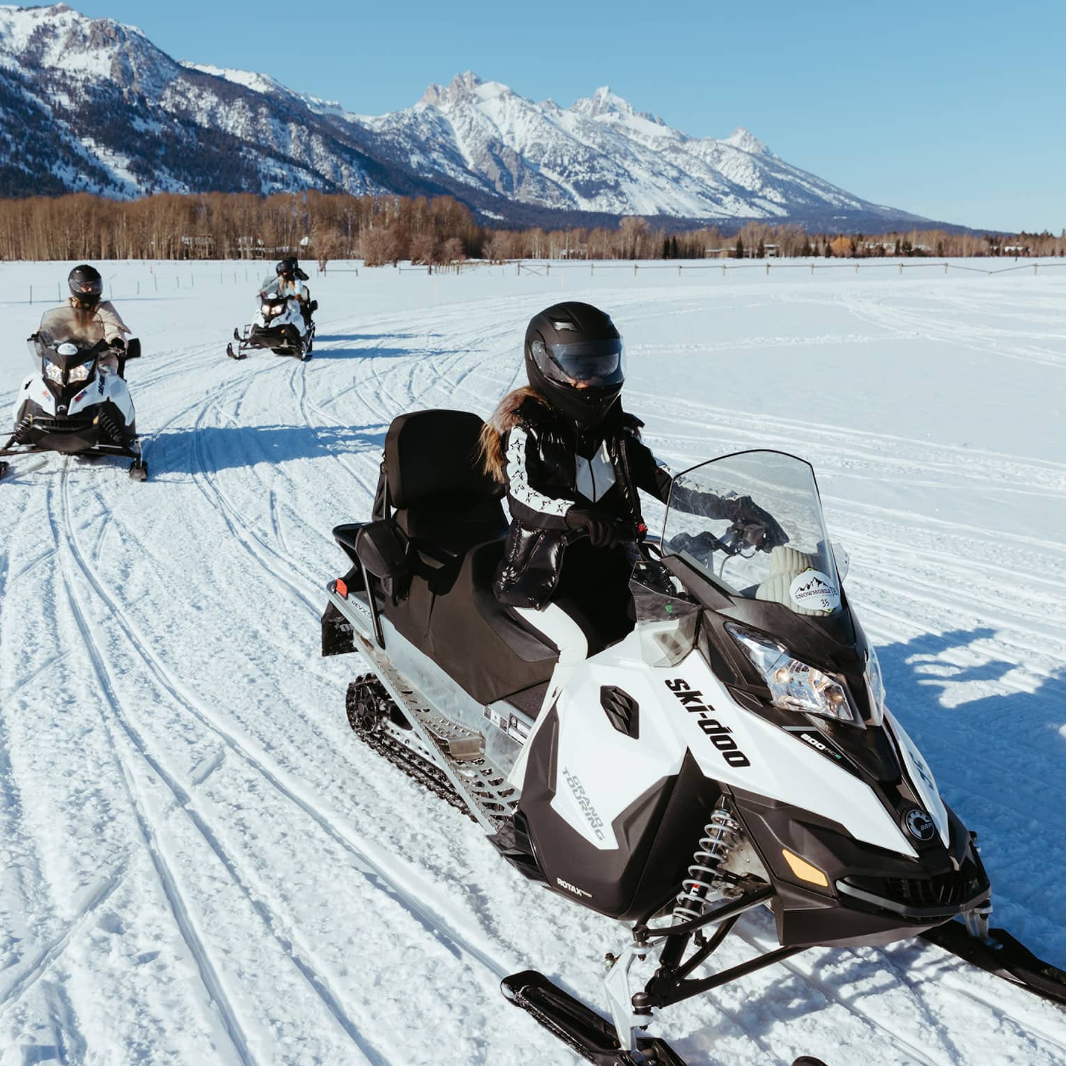 Three people on snowbmobiles.