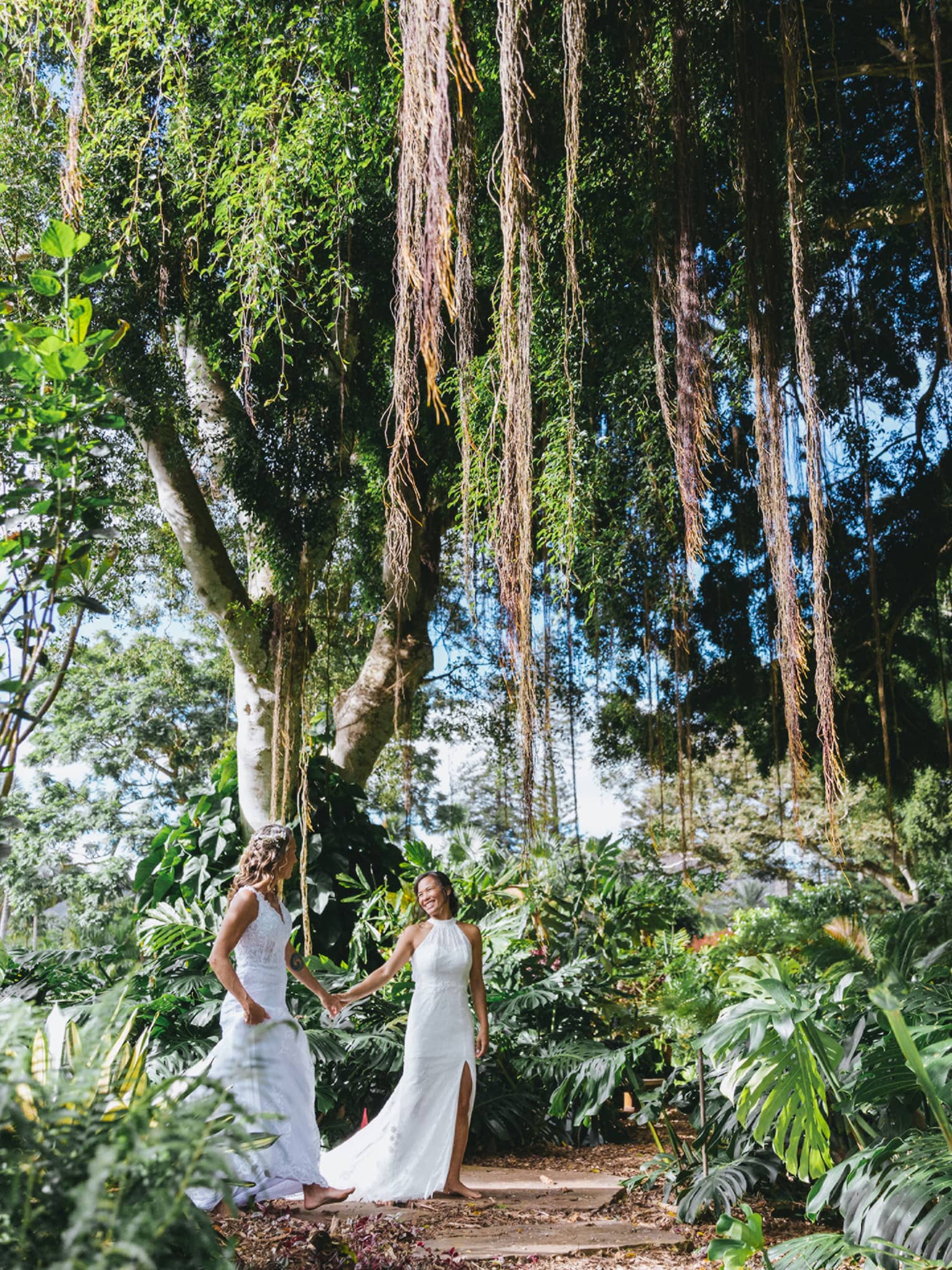 Two brides walk hand in hand in a tropical forest
