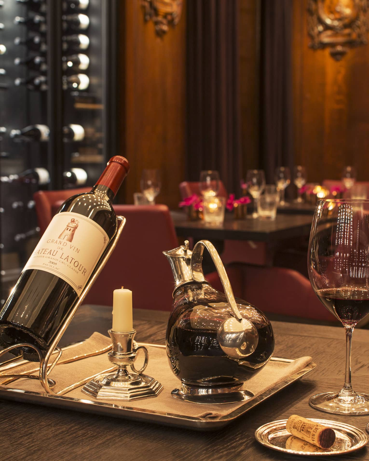 A bottle of red wine, a decanter and two glasses in a dimly lit restaurant.