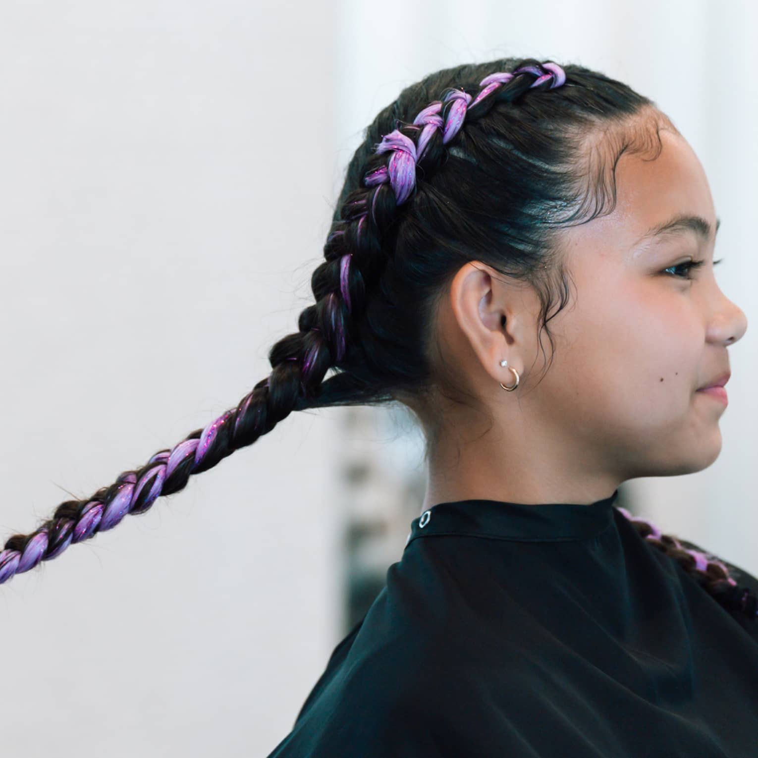 A young girl gets her hair braided at salon