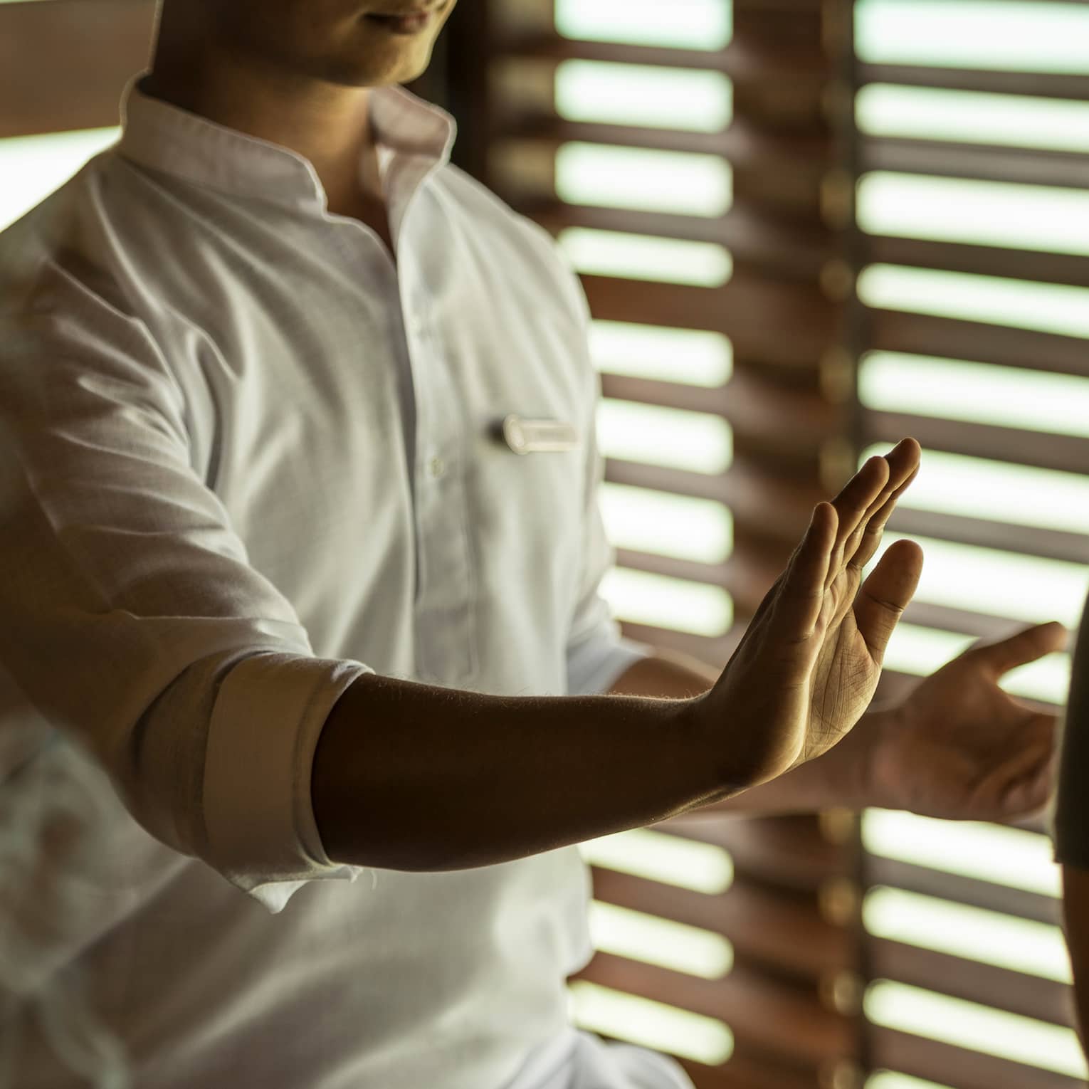 Reiki healer with eyes closed holds hand over woman's body