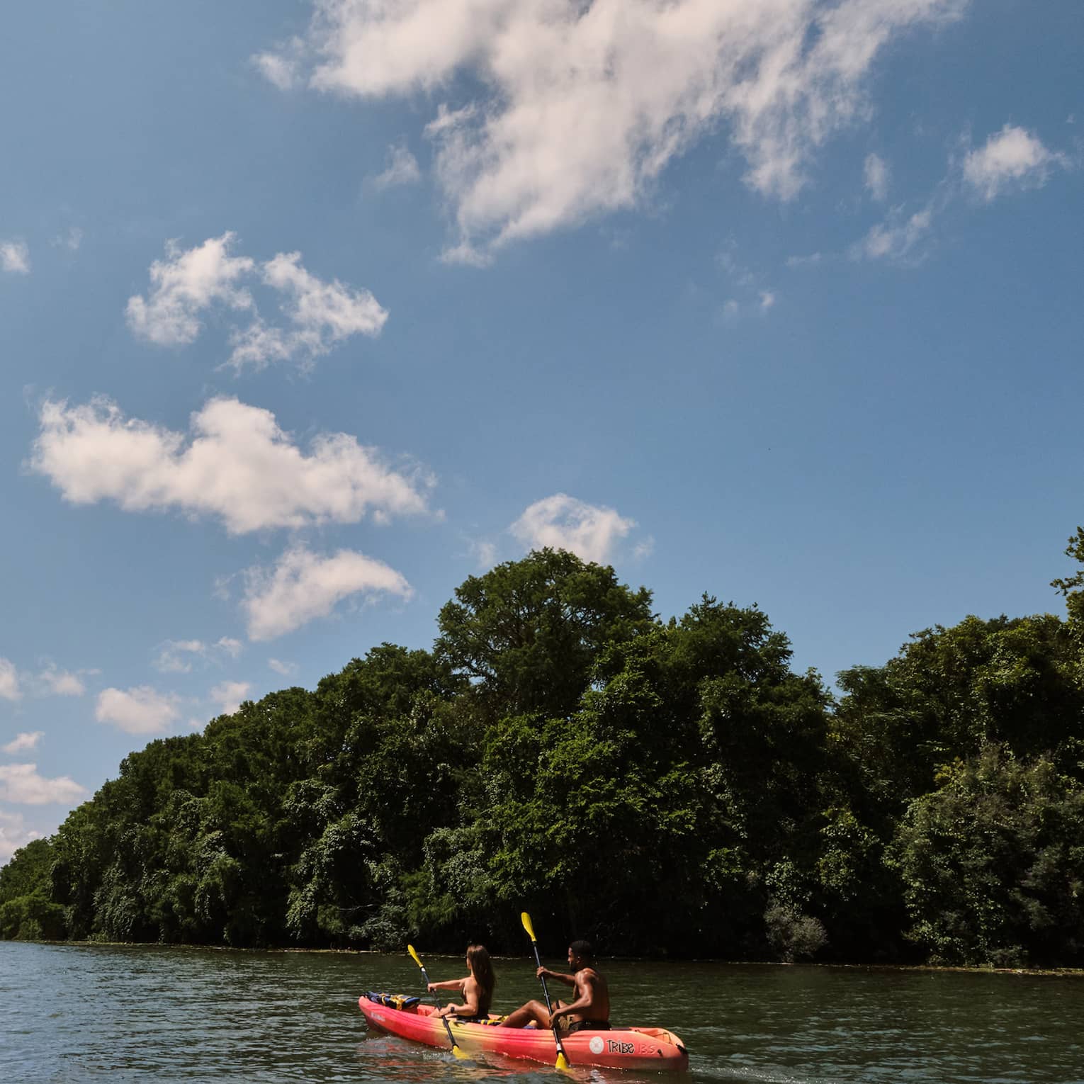 Two guests on a kayak using oars to move the kayak through the water