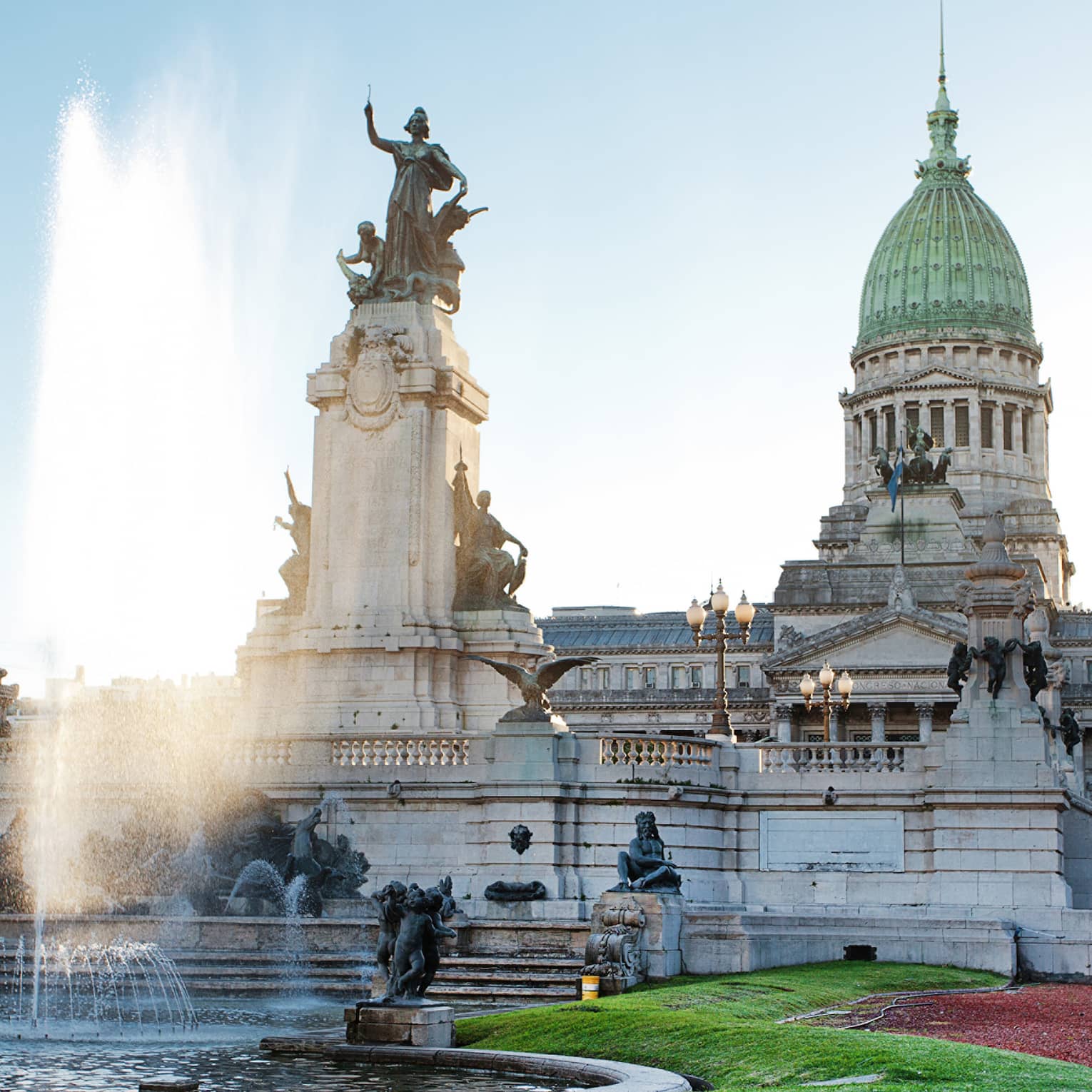 Large fountain, historic building and courtyard on sunny day