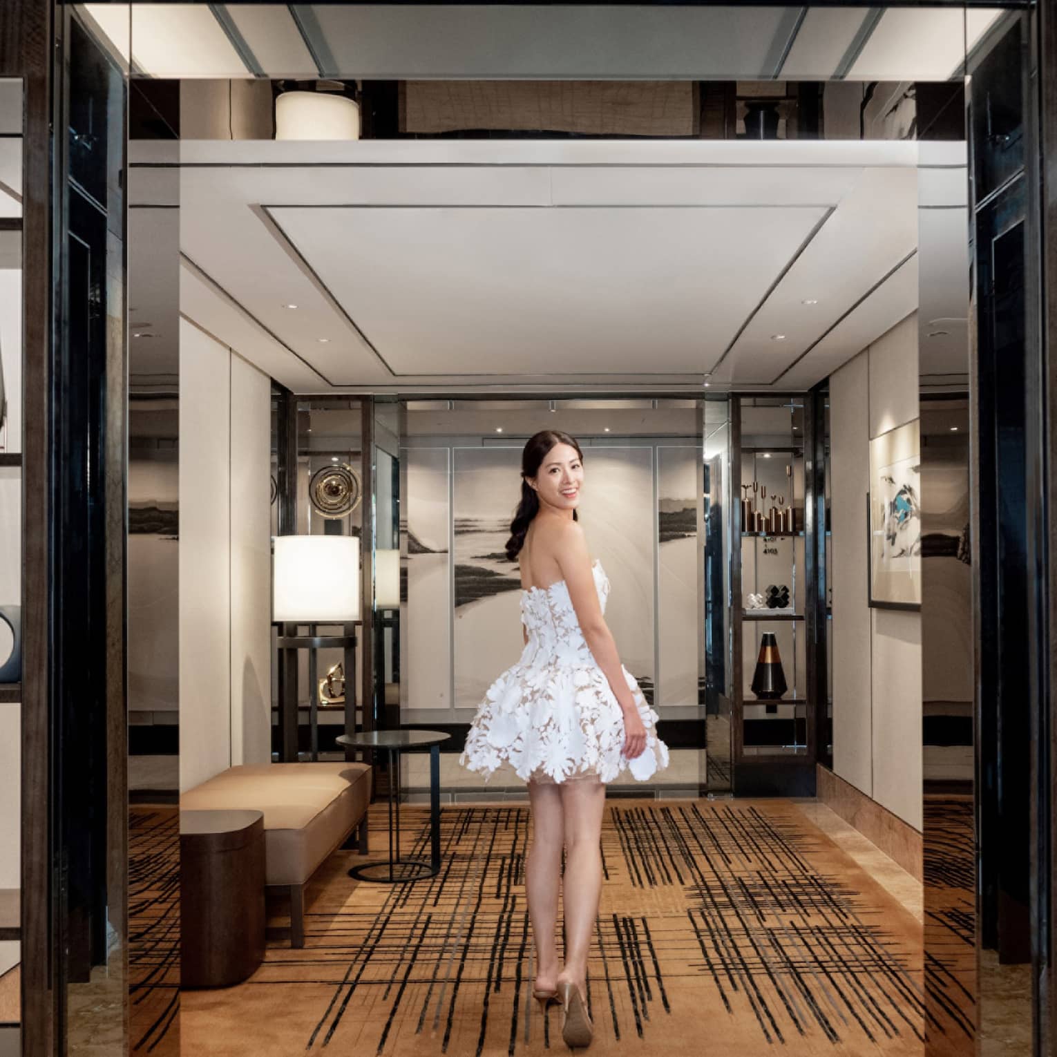 Woman looks back as she walks through hotel suite